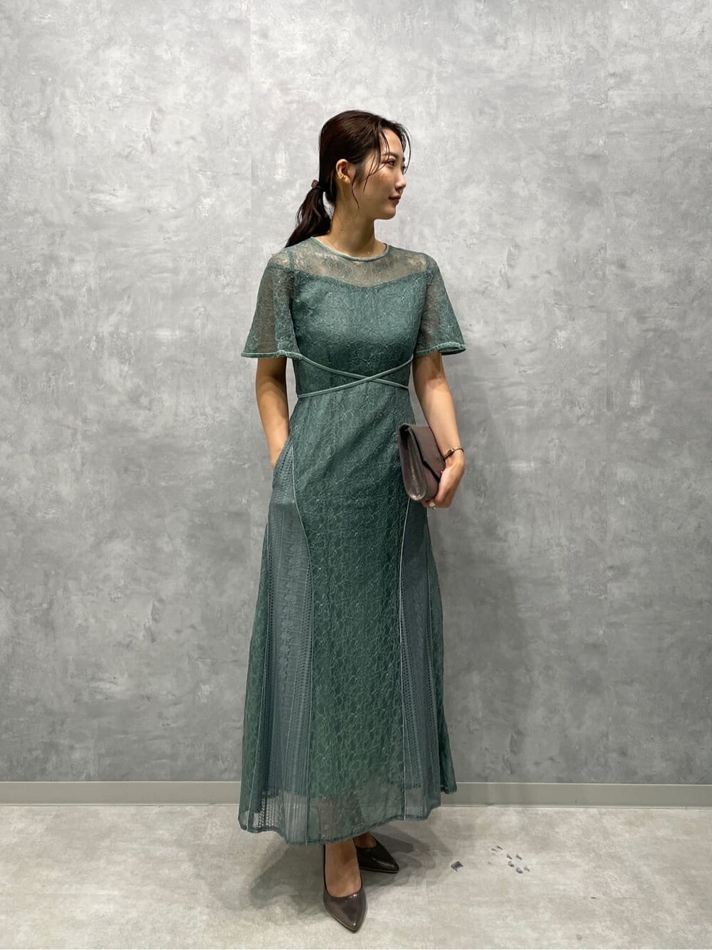 シルバー系のパンプス、シルバー系のクラッチバッグ、グリーン系のドレスを着用したレディースの夏コーディネートの5枚目の写真