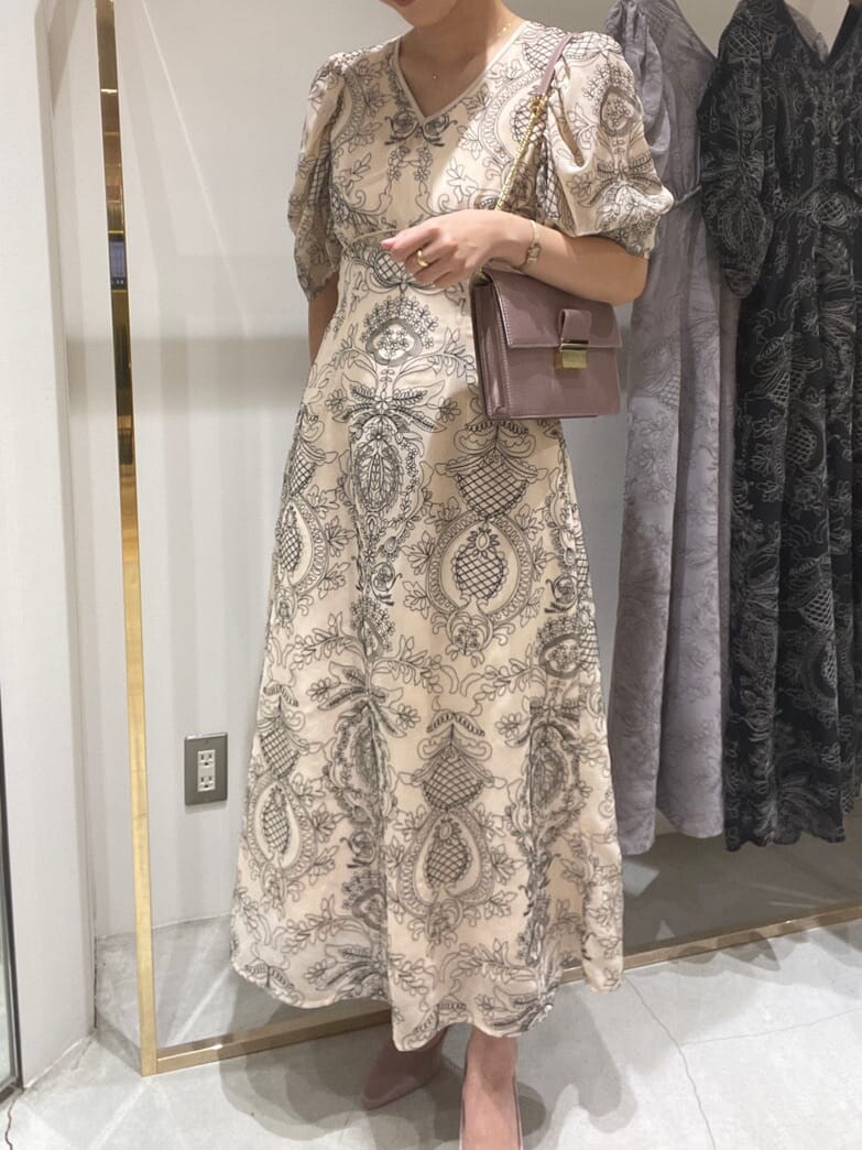 ベージュ系のドレス、ピンク系のパンプス、ピンク系のクラッチバッグを着用したレディースの春コーディネートの2枚目の写真