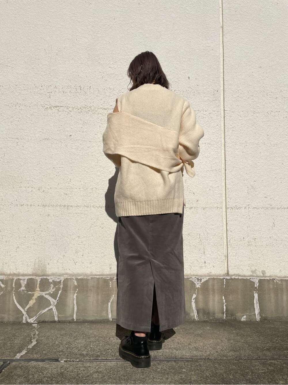 グレー系のスカート、ホワイト系のニット/セーターを着用したレディースの冬コーディネートの7枚目の写真