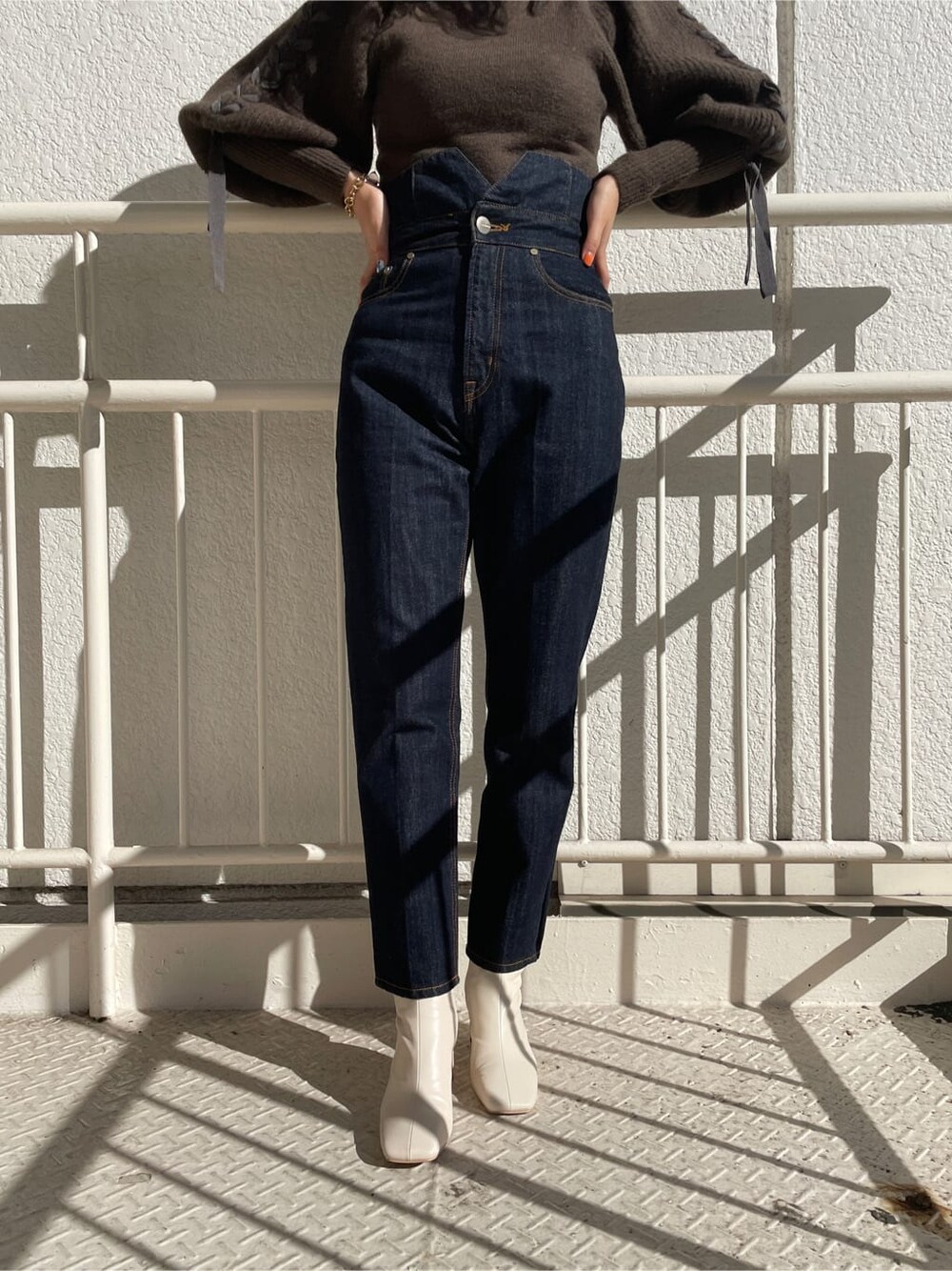 ホワイト系のその他シューズ、ブラウン系のニット/セーター、ブルー系のデニムパンツを着用したレディースの冬コーディネートの8枚目の写真