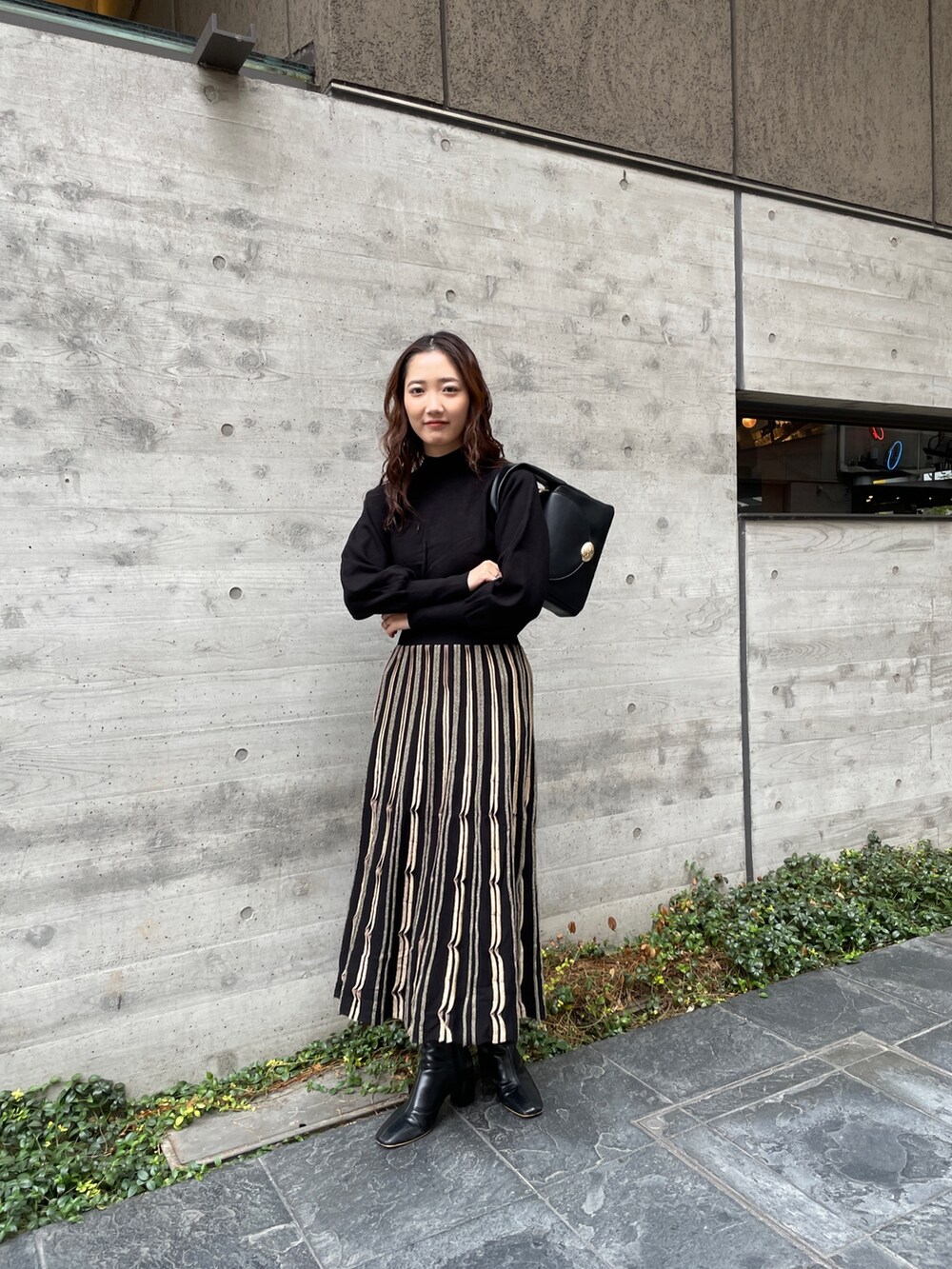 ブルー系のノーカラーコート、ブラック系のワンピース、ブラック系のブーツを着用したレディースの冬コーディネートの7枚目の写真