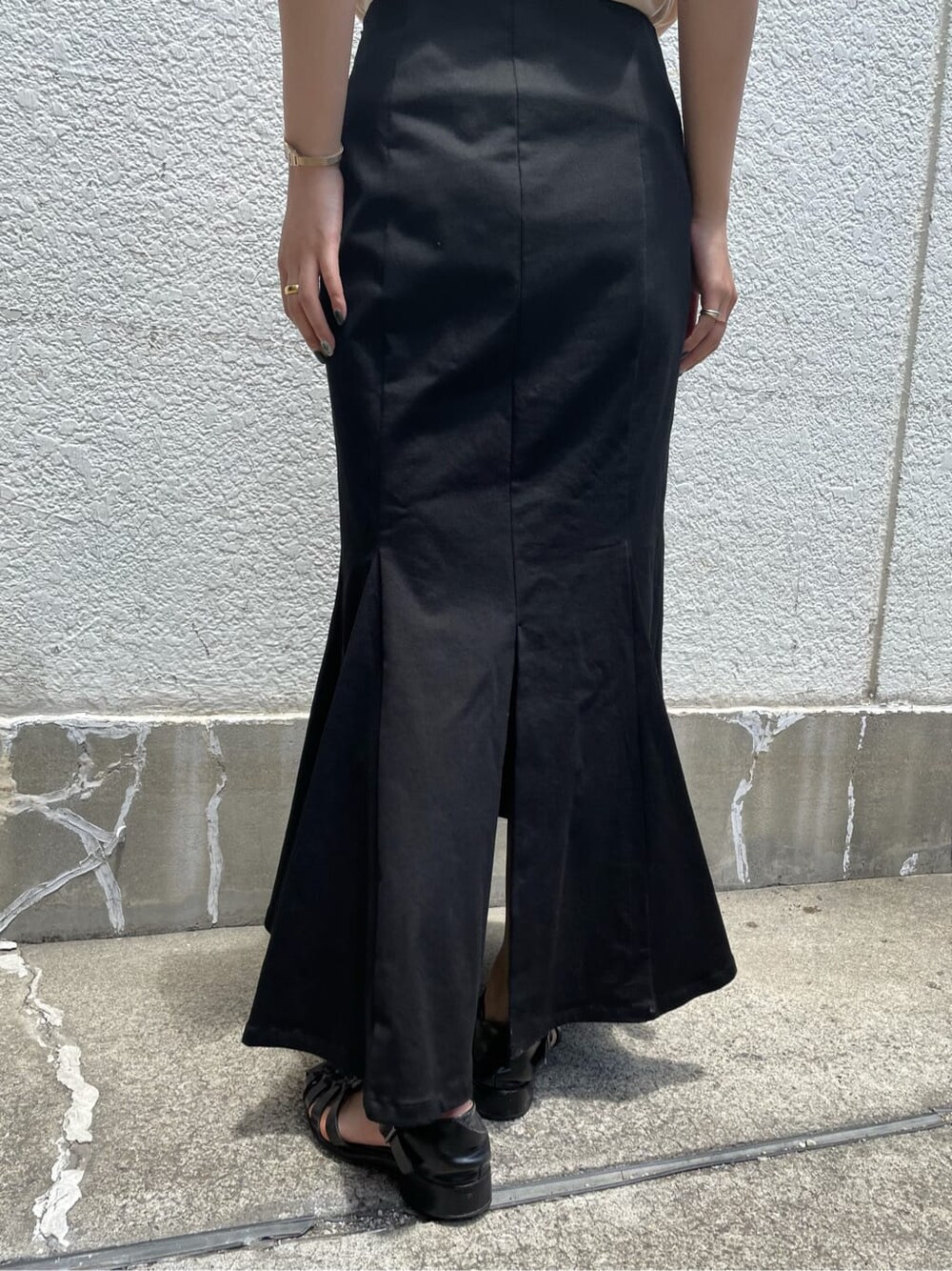 ブラック系のスカート、ベージュ系のニット/セーターを着用したレディースの夏コーディネートの3枚目の写真