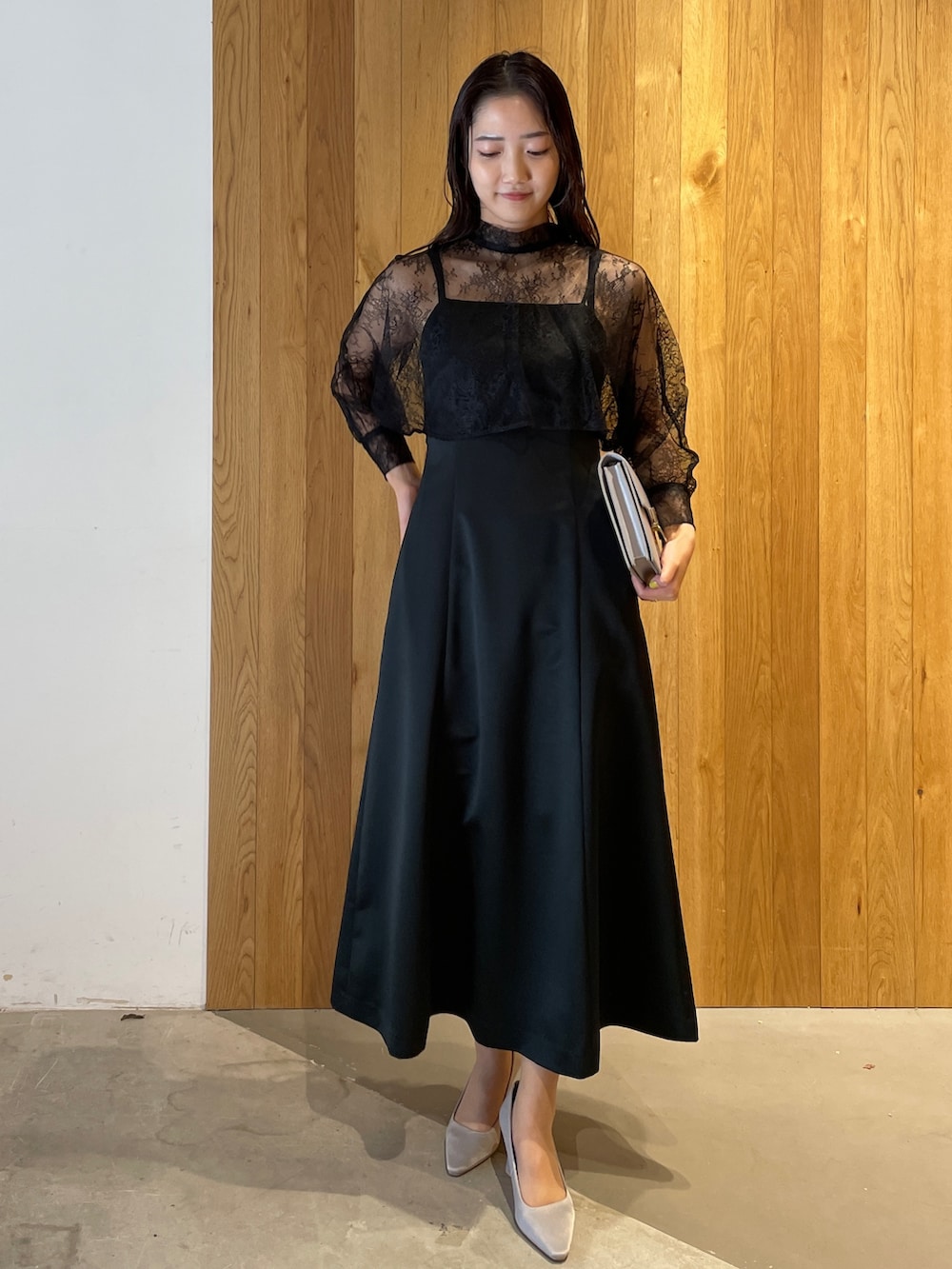 グレー系のパンプス、ブラック系のドレス、グレー系のクラッチバッグを着用したレディースの冬コーディネートの2枚目の写真