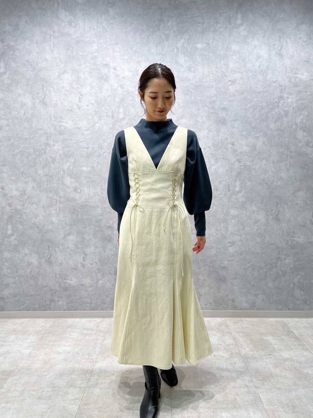 グリーン系のニット/セーター、ホワイト系のカーディガン/ボレロ、ブラック系のブーツを着用したレディースの冬コーディネートの4枚目の写真