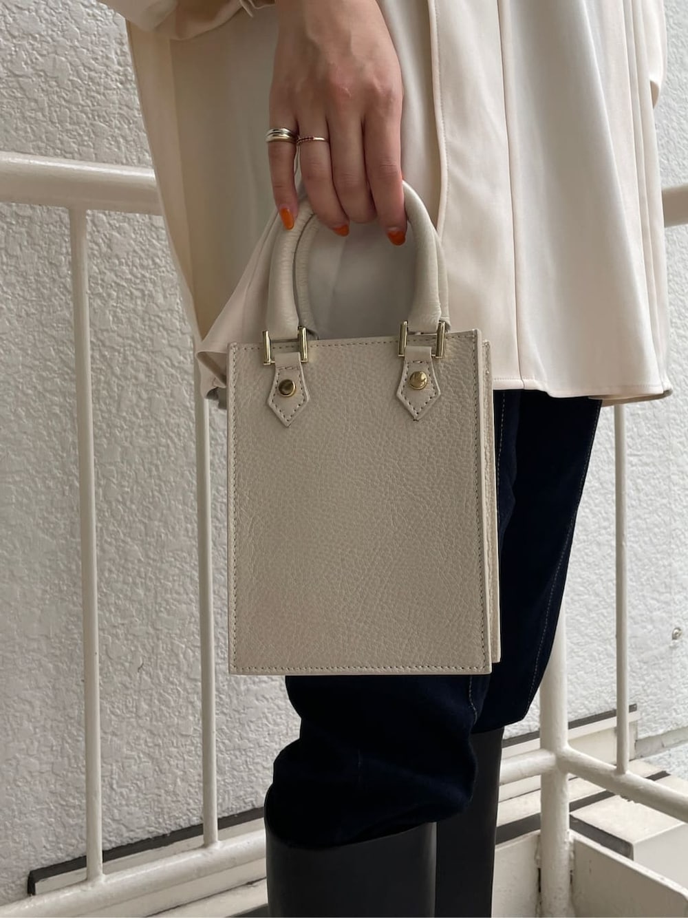 ブラック系のブーツ、ホワイト系のショルダーバッグ、ブルー系のデニムパンツを着用したレディースの秋コーディネートの7枚目の写真