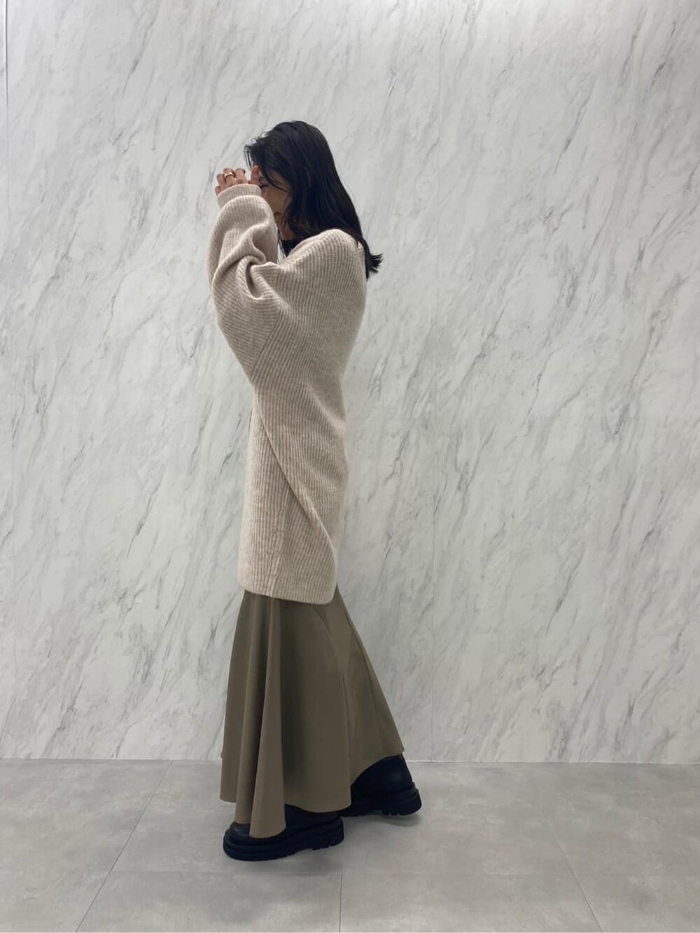 ブラック系のブーツ、ベージュ系のスカート、ホワイト系のカーディガン/ボレロを着用したレディースの秋コーディネートの5枚目の写真