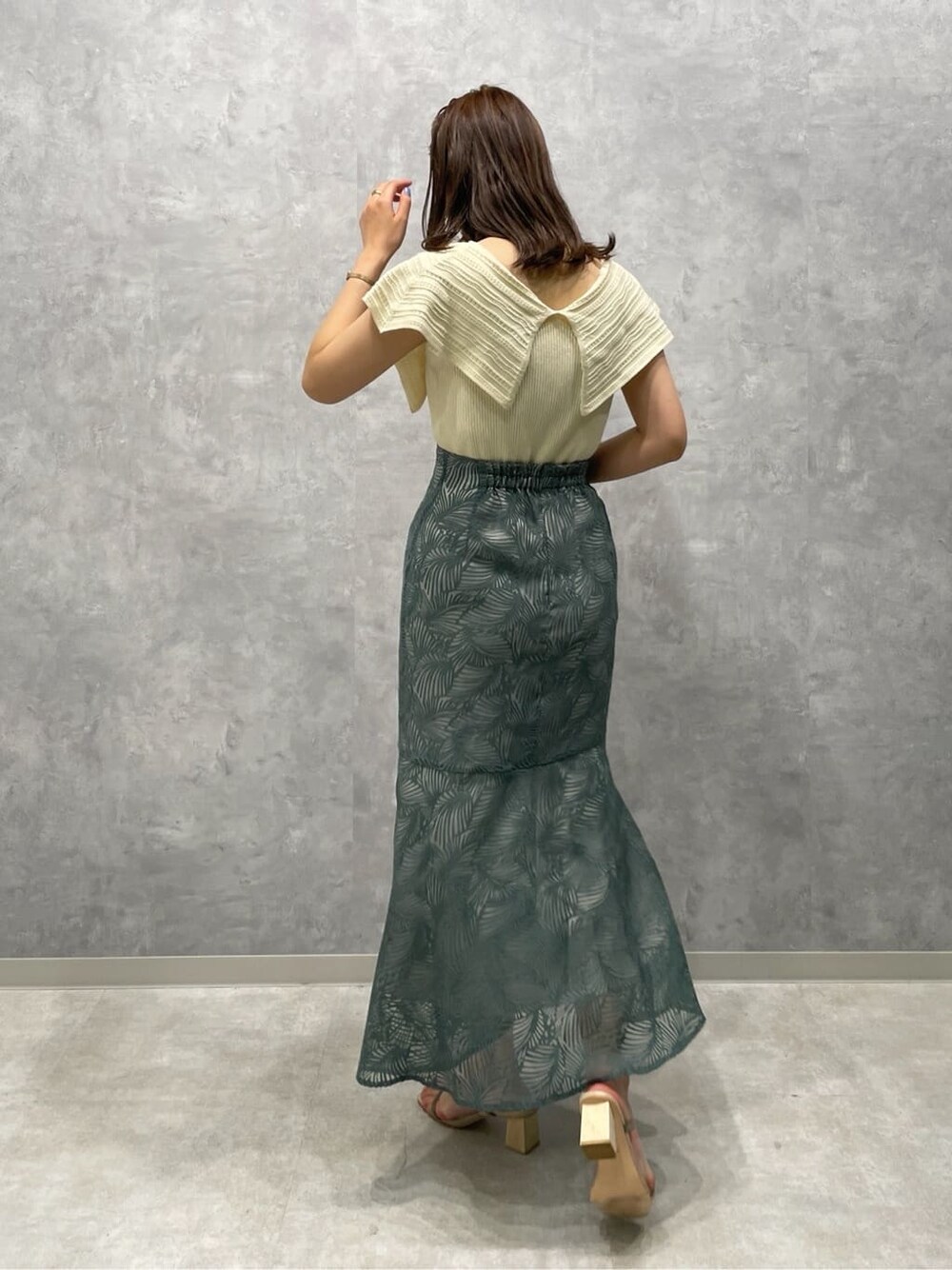 グリーン系のサンダル、ブルー系のスカート、ホワイト系のニット/セーターを着用したレディースの夏コーディネートの4枚目の写真