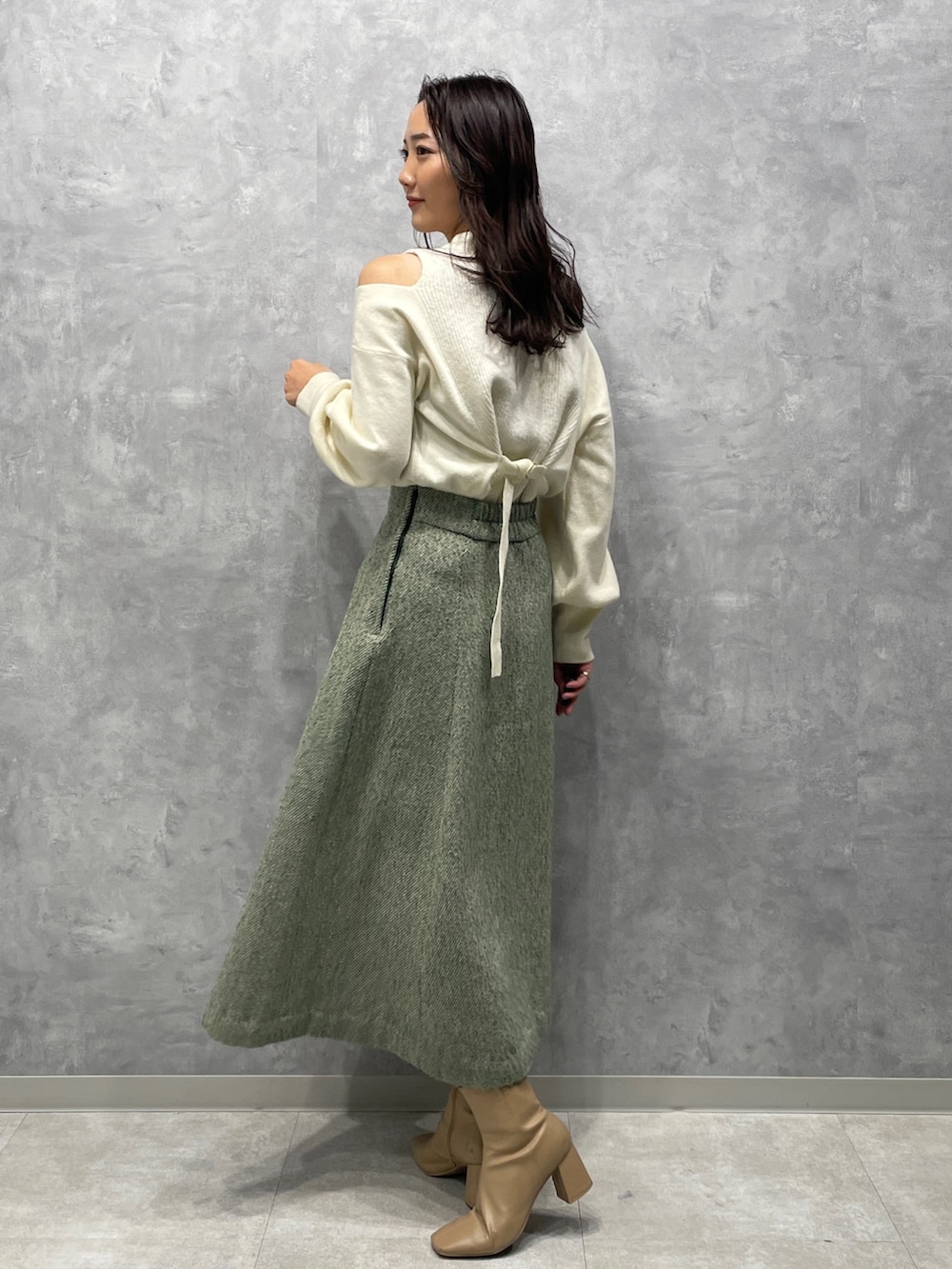 ベージュ系のブーツ、ホワイト系のニット/セーター、グリーン系のスカートを着用したレディースの冬コーディネートの5枚目の写真