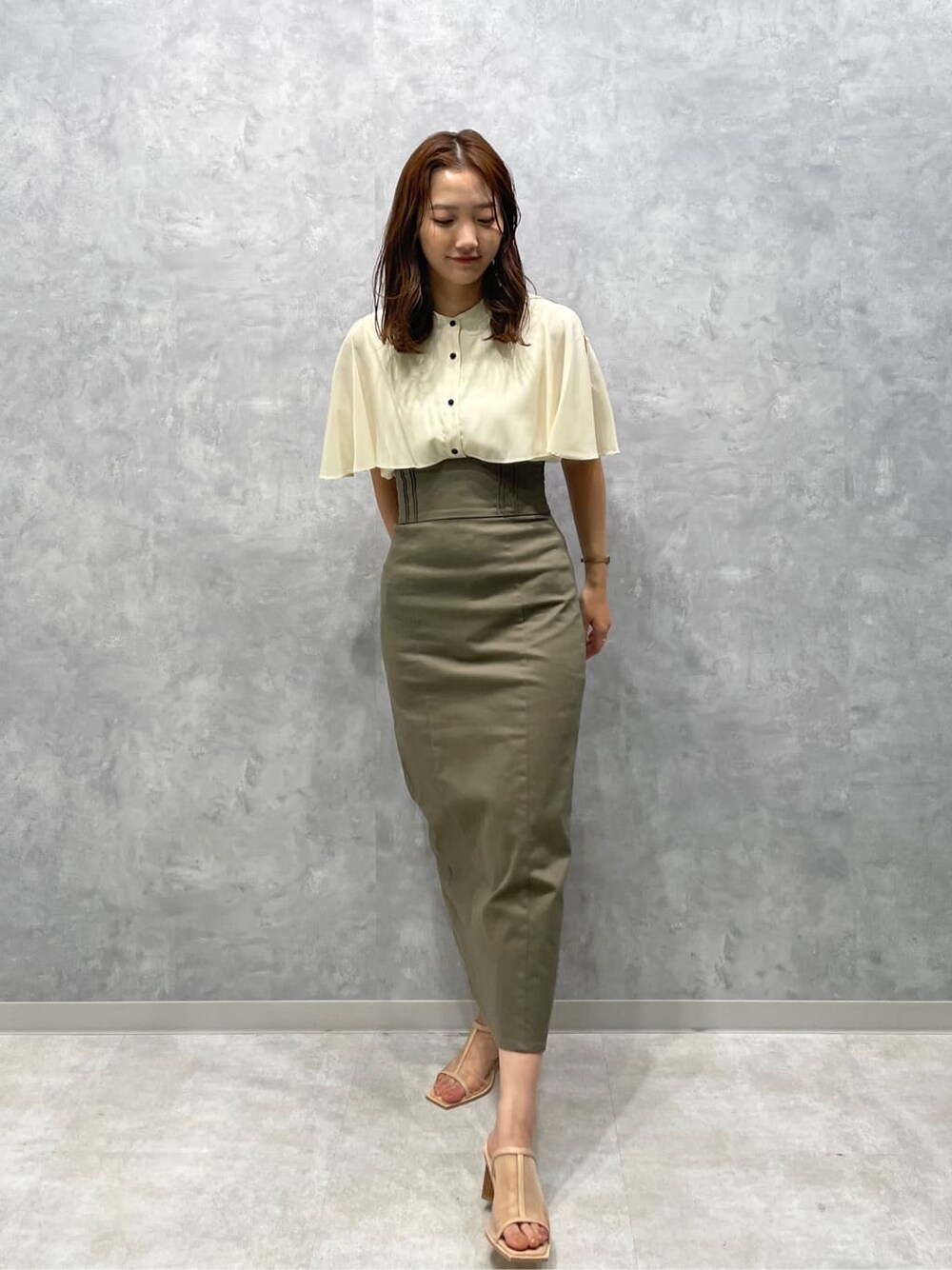 ベージュ系のスカート、ベージュ系のサンダル、ホワイト系のシャツ/ブラウスを着用したレディースの夏コーディネートの3枚目の写真