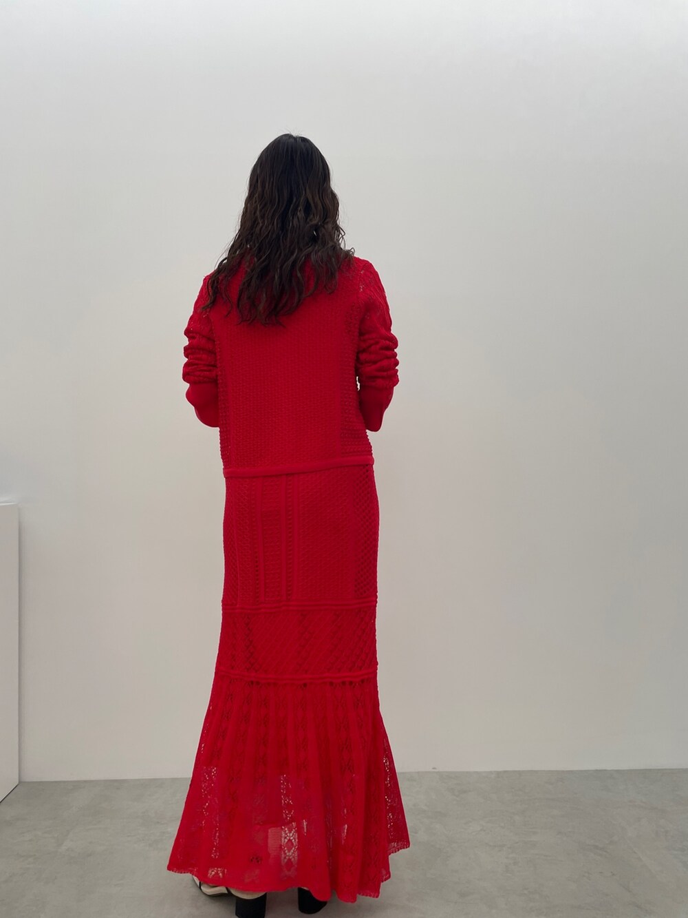 レッド系のカーディガン/ボレロ、レッド系のスカート、ブラック系のサンダルを着用したレディースの春コーディネートの6枚目の写真