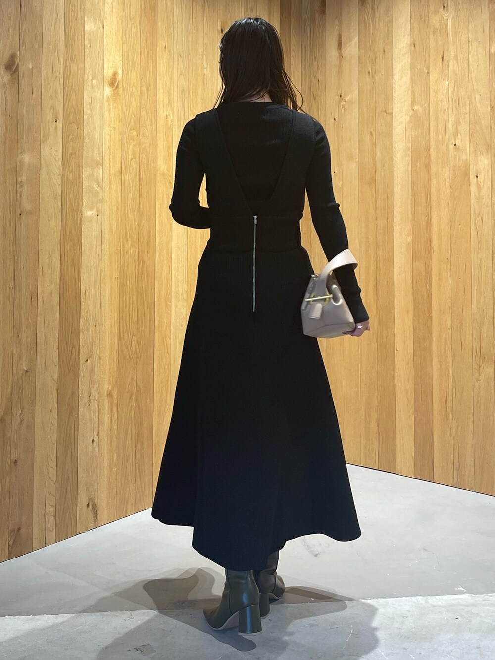 ベージュ系のハンドバッグ、グリーン系のブーツ、ブラック系のスカートを着用したレディースの秋コーディネートの5枚目の写真