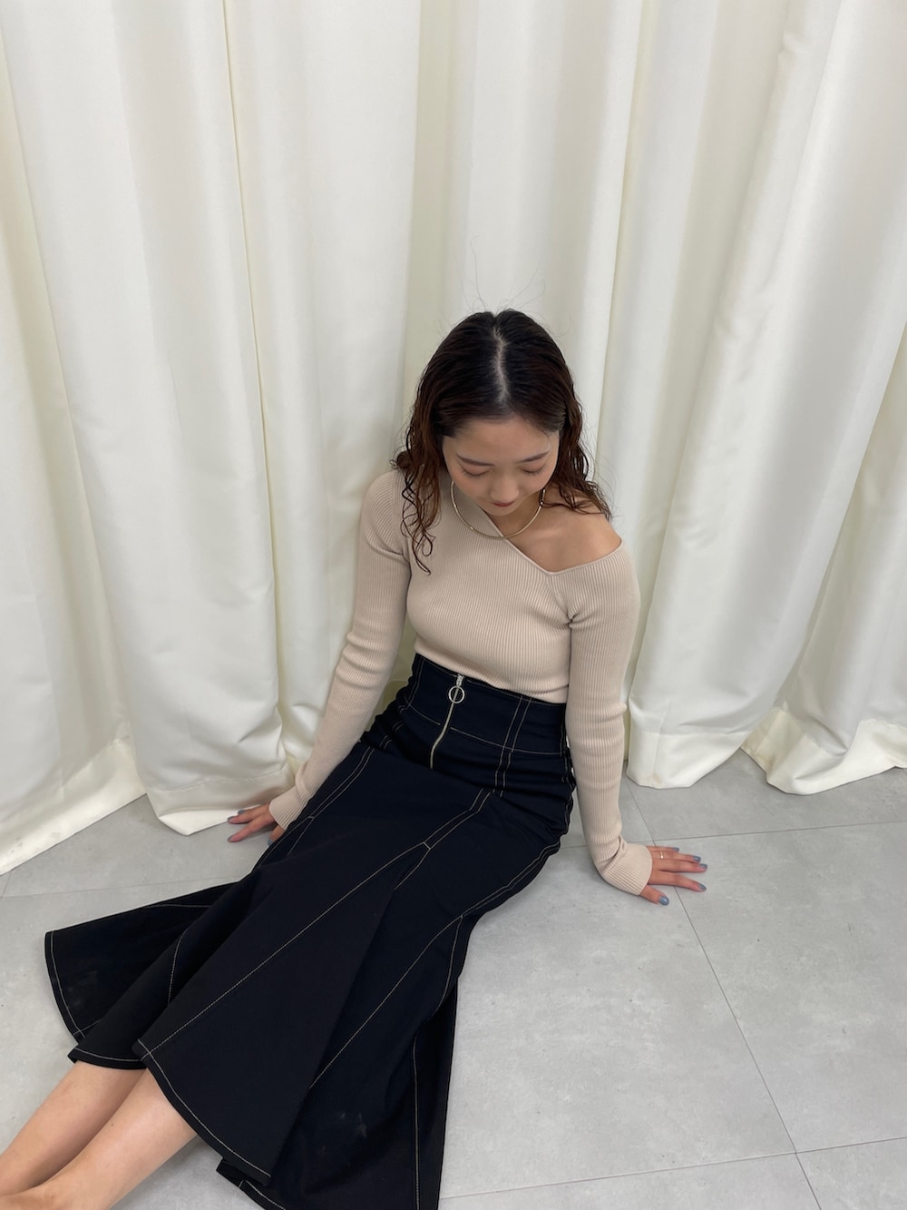 ブラック系のスカート、ベージュ系のニット/セーター、ホワイト系のパンプスを着用したレディースの冬コーディネートの2枚目の写真