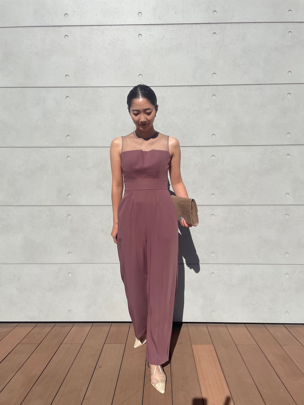 ピンク系のパンツドレス、ゴールド系のハンドバッグ、ベージュ系のパンプスを着用したレディースの秋コーディネートの5枚目の写真