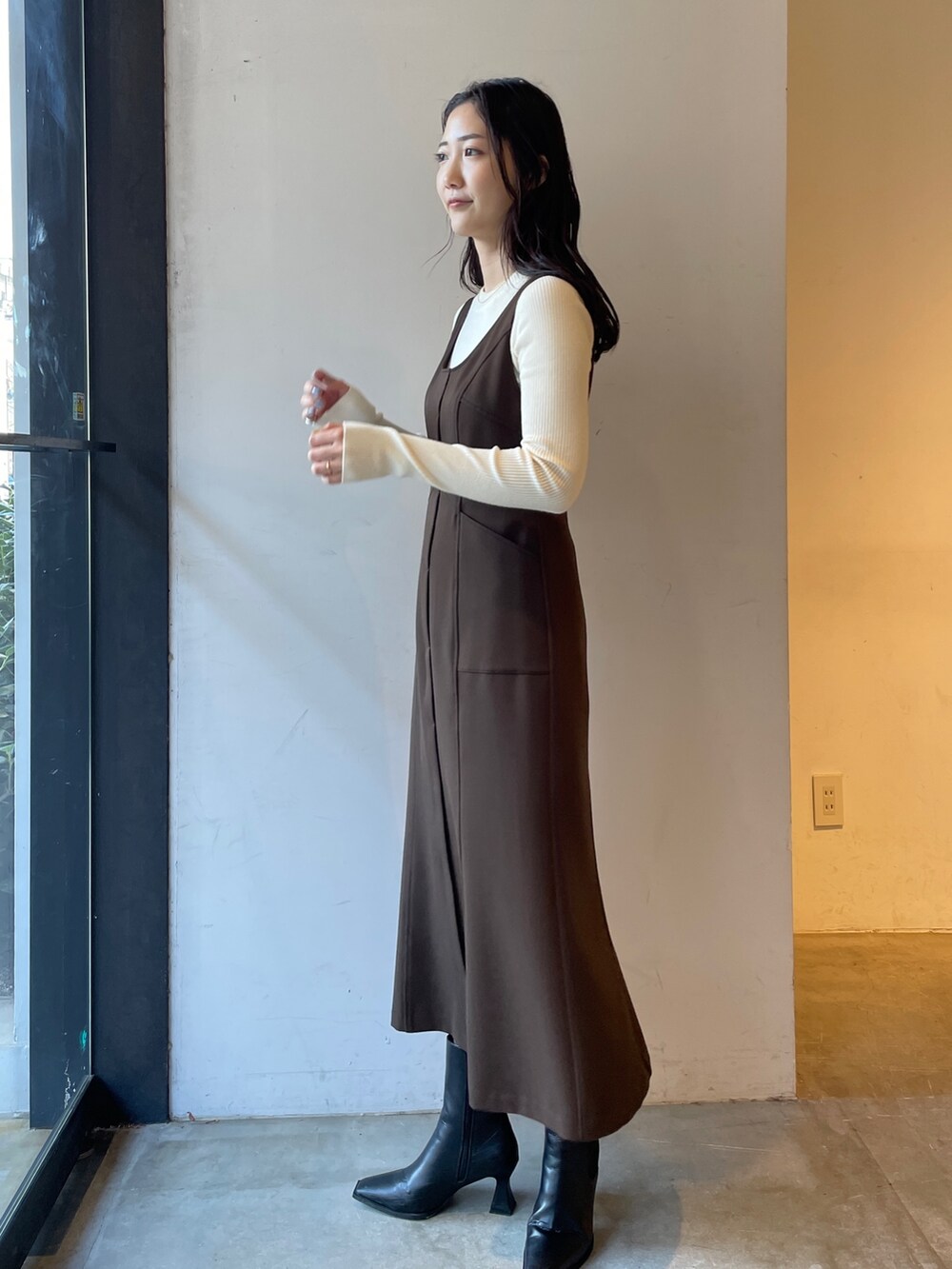 ブラック系のブーツ、ホワイト系のニット/セーター、ブラウン系のジャンパースカートを着用したレディースの冬コーディネートの4枚目の写真