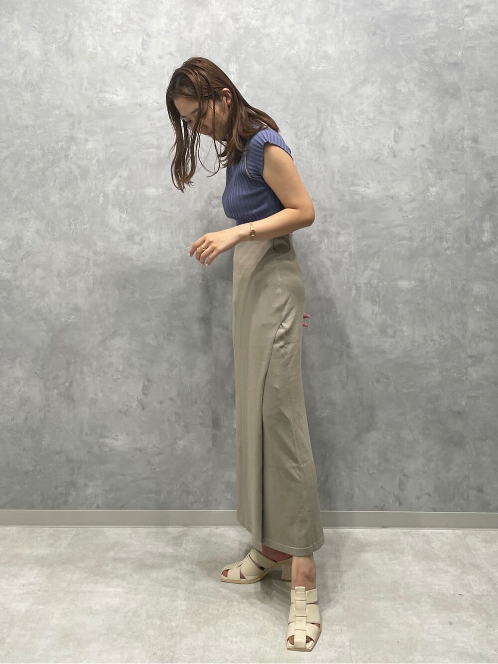 ホワイト系のサンダル、ベージュ系のスカート、ブルー系のニット/セーターを着用したレディースの夏コーディネートの3枚目の写真