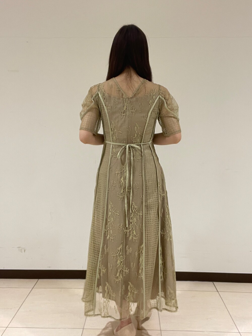 ベージュ系のパンプス、グリーン系のドレスを着用したレディースの春コーディネートの4枚目の写真