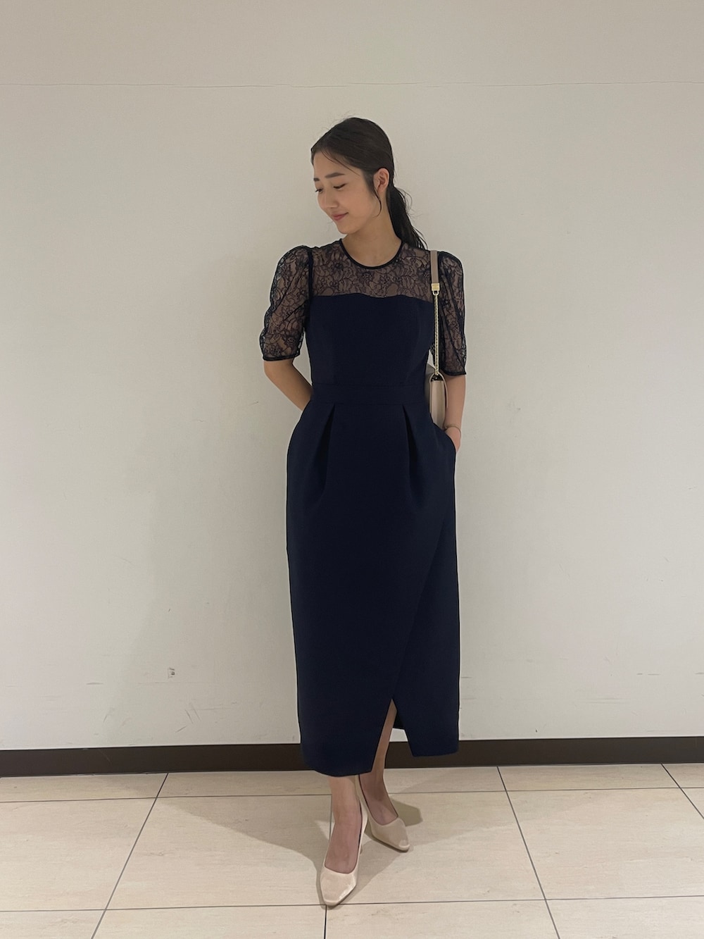 ゴールド系のクラッチバッグ、ベージュ系のパンプス、ブルー系のドレスを着用したレディースの春コーディネートの2枚目の写真