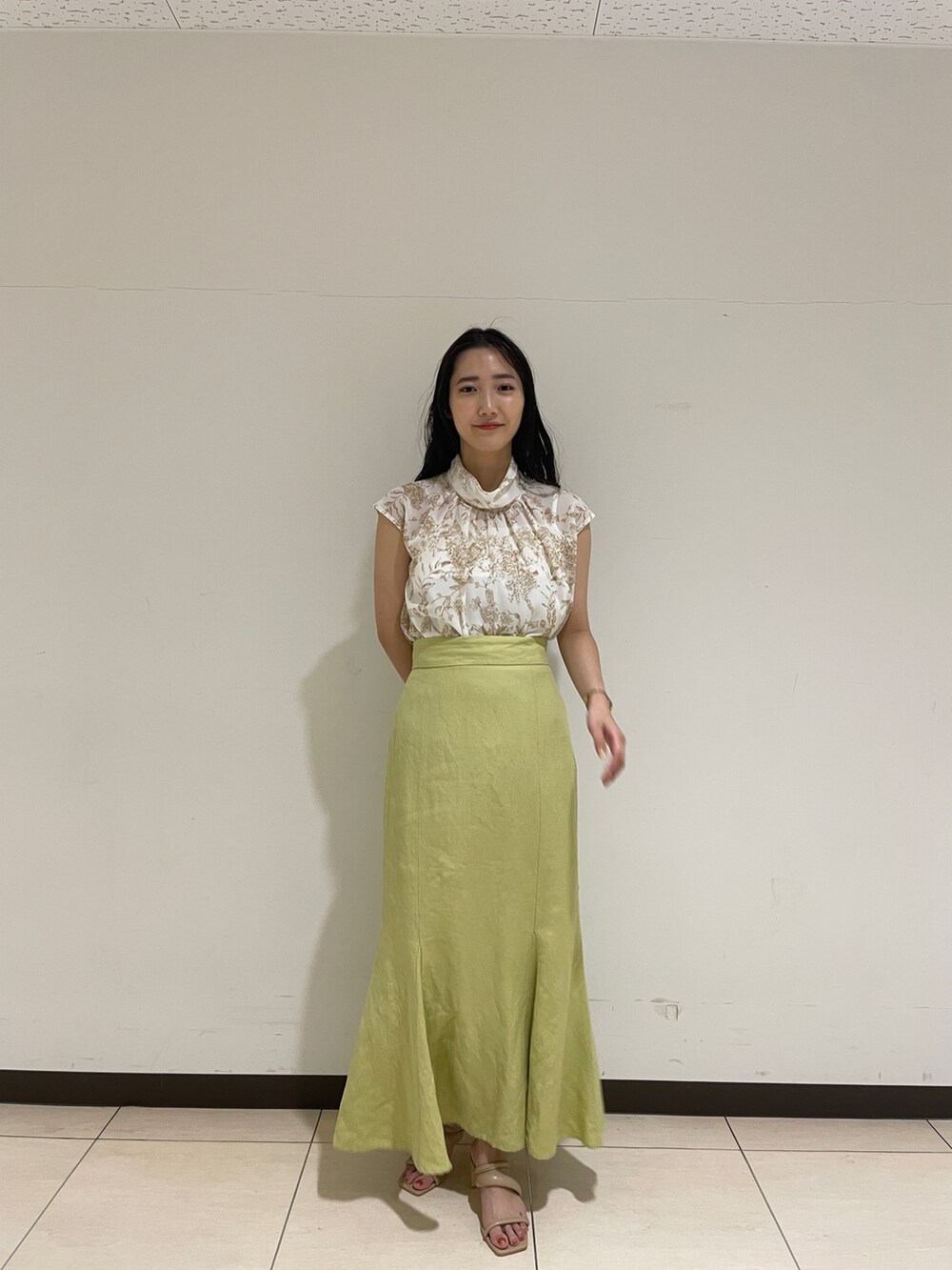 ベージュ系のシャツ/ブラウス、グリーン系のスカート、ベージュ系のサンダルを着用したレディースの春コーディネートの2枚目の写真