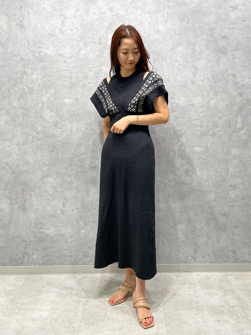 ベージュ系のサンダル、ブラック系のワンピースを着用したレディースの春コーディネートの2枚目の写真