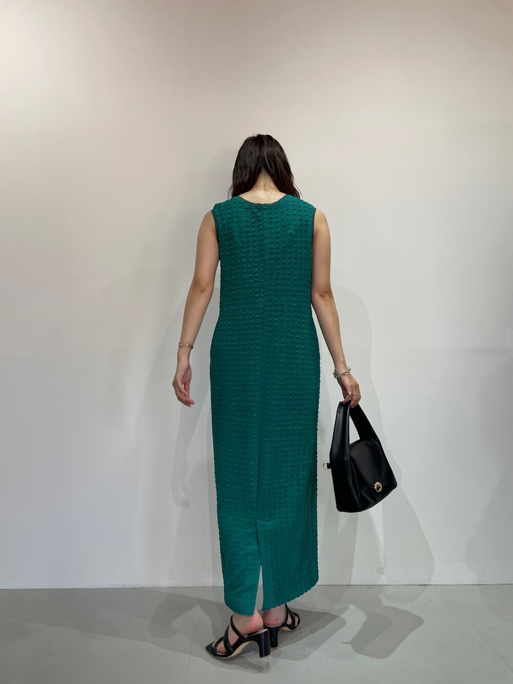 グリーン系のワンピース、ブラック系のサンダル、ブラック系のハンドバッグを着用したレディースの夏コーディネートの6枚目の写真