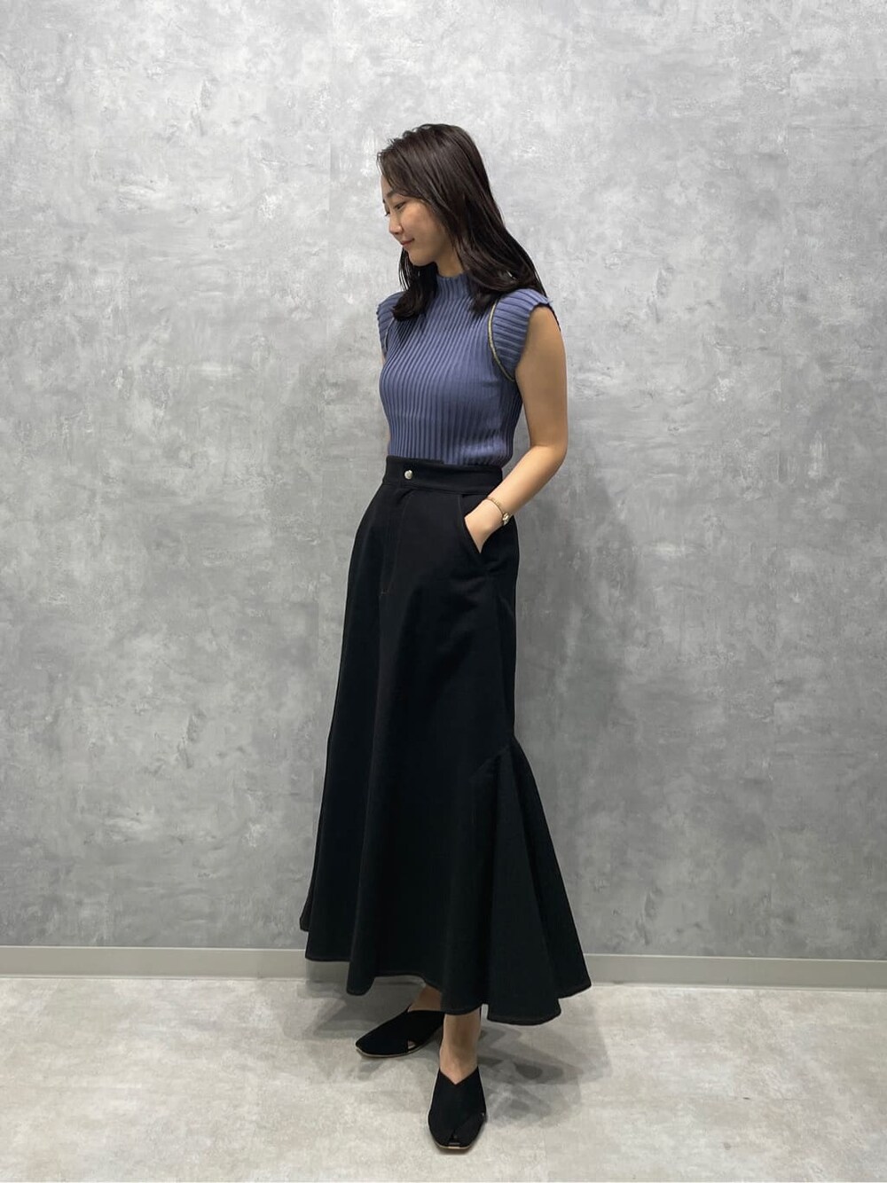 ブラック系のサンダル、ブラック系のスカート、ブルー系のニット/セーターを着用したレディースの夏コーディネートの2枚目の写真