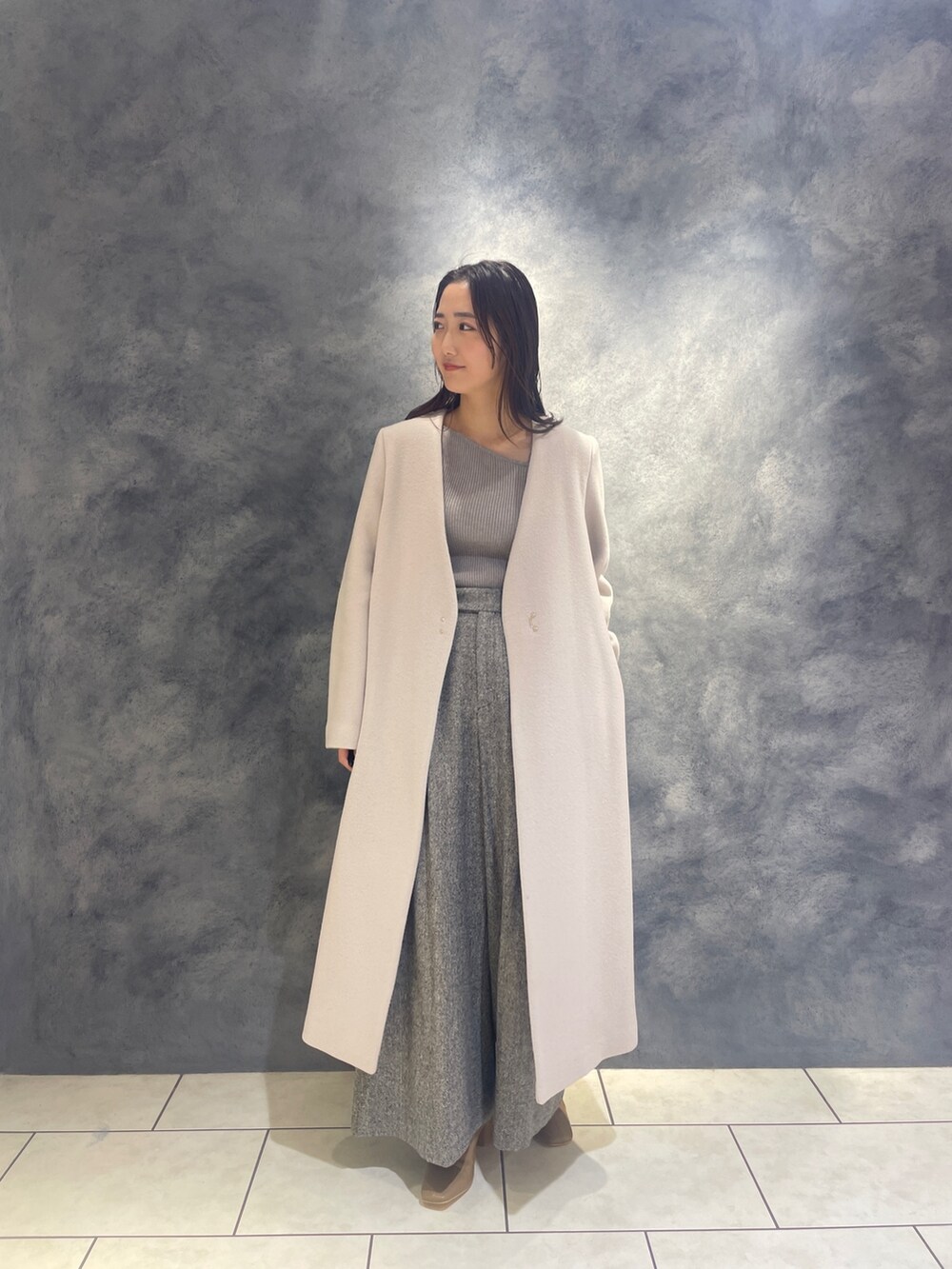 ホワイト系のノーカラーコート、グレー系のニット/セーター、ブラック系のその他パンツを着用したレディースの秋コーディネートの2枚目の写真