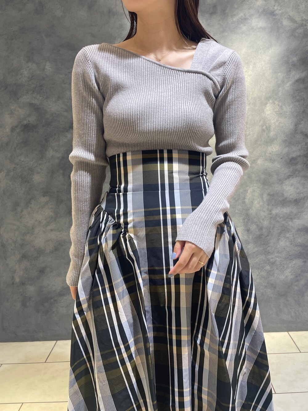 グレー系のニット/セーター、ベージュ系のブーツ、オレンジ系のスカートを着用したレディースの秋コーディネートの6枚目の写真