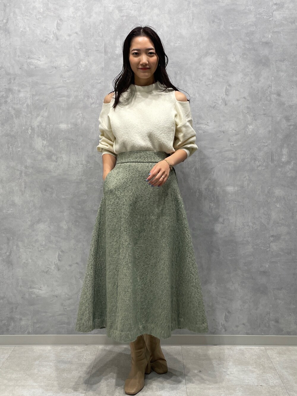 ベージュ系のブーツ、ホワイト系のニット/セーター、グリーン系のスカートを着用したレディースの冬コーディネートの3枚目の写真