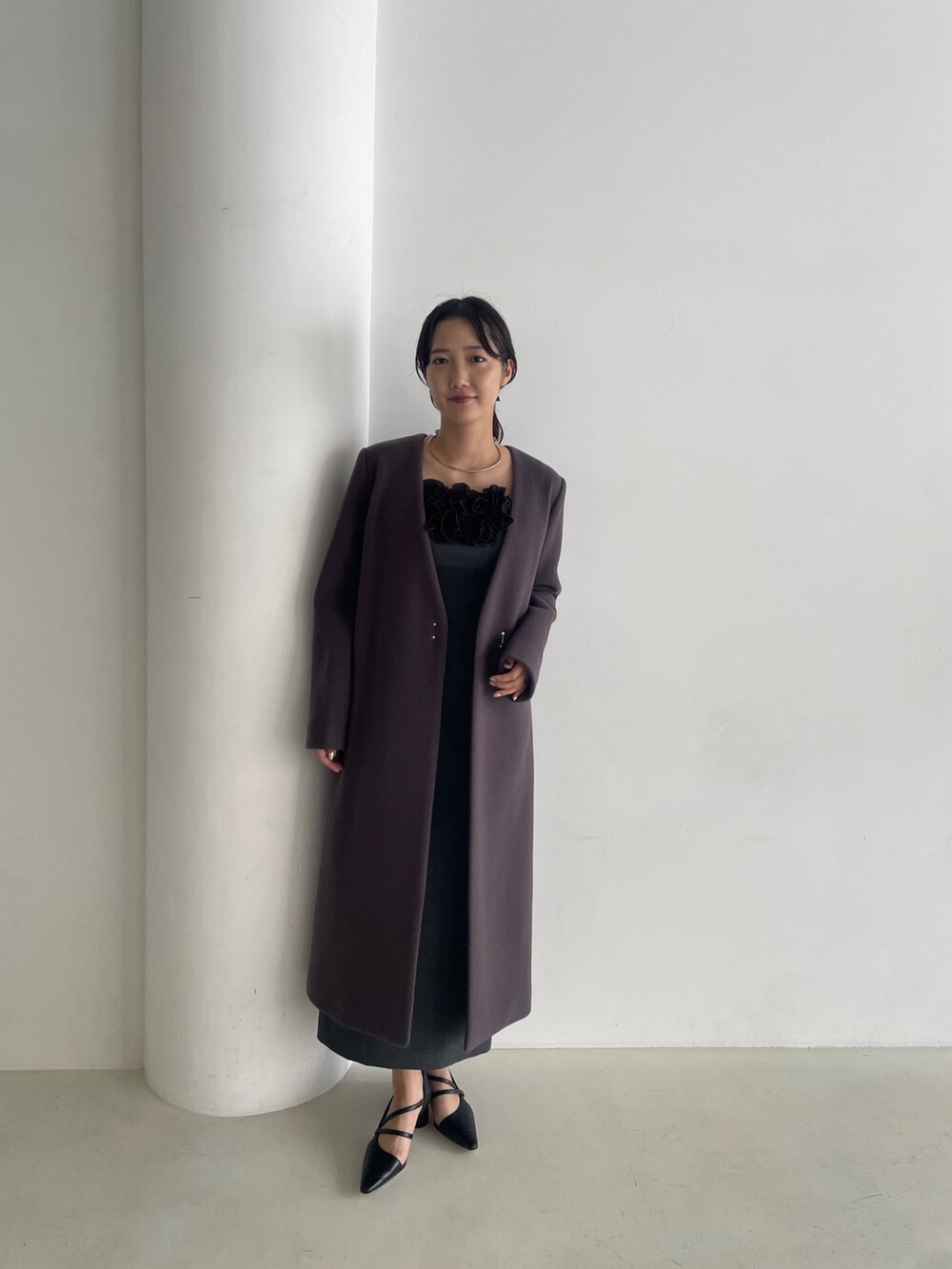 グレー系のドレス、ブラック系のパンプス、グレー系のチェスターコートを着用したレディースの秋コーディネートの2枚目の写真