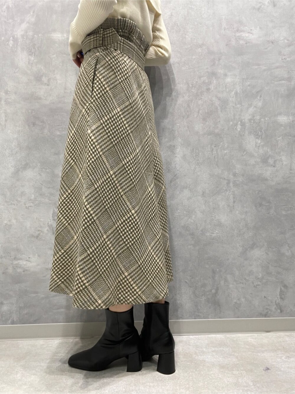 ブラック系のブーツ、ベージュ系のスカート、ホワイト系のニット/セーターを着用したレディースの秋コーディネートの10枚目の写真