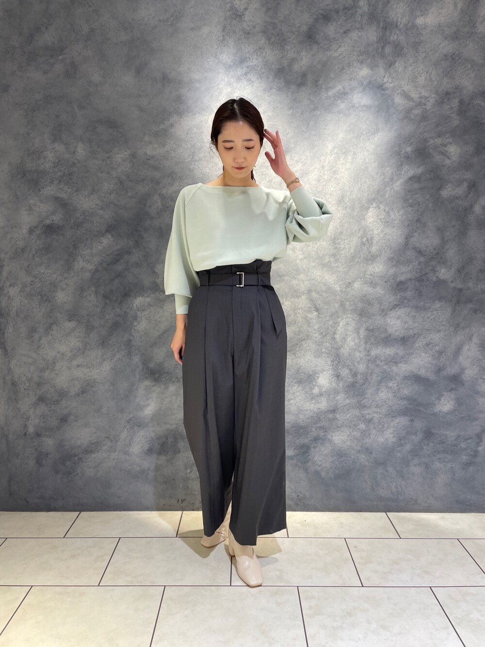 グレー系のその他パンツ、ホワイト系のブーツ、グリーン系のニット/セーターを着用したレディースの冬コーディネートの4枚目の写真