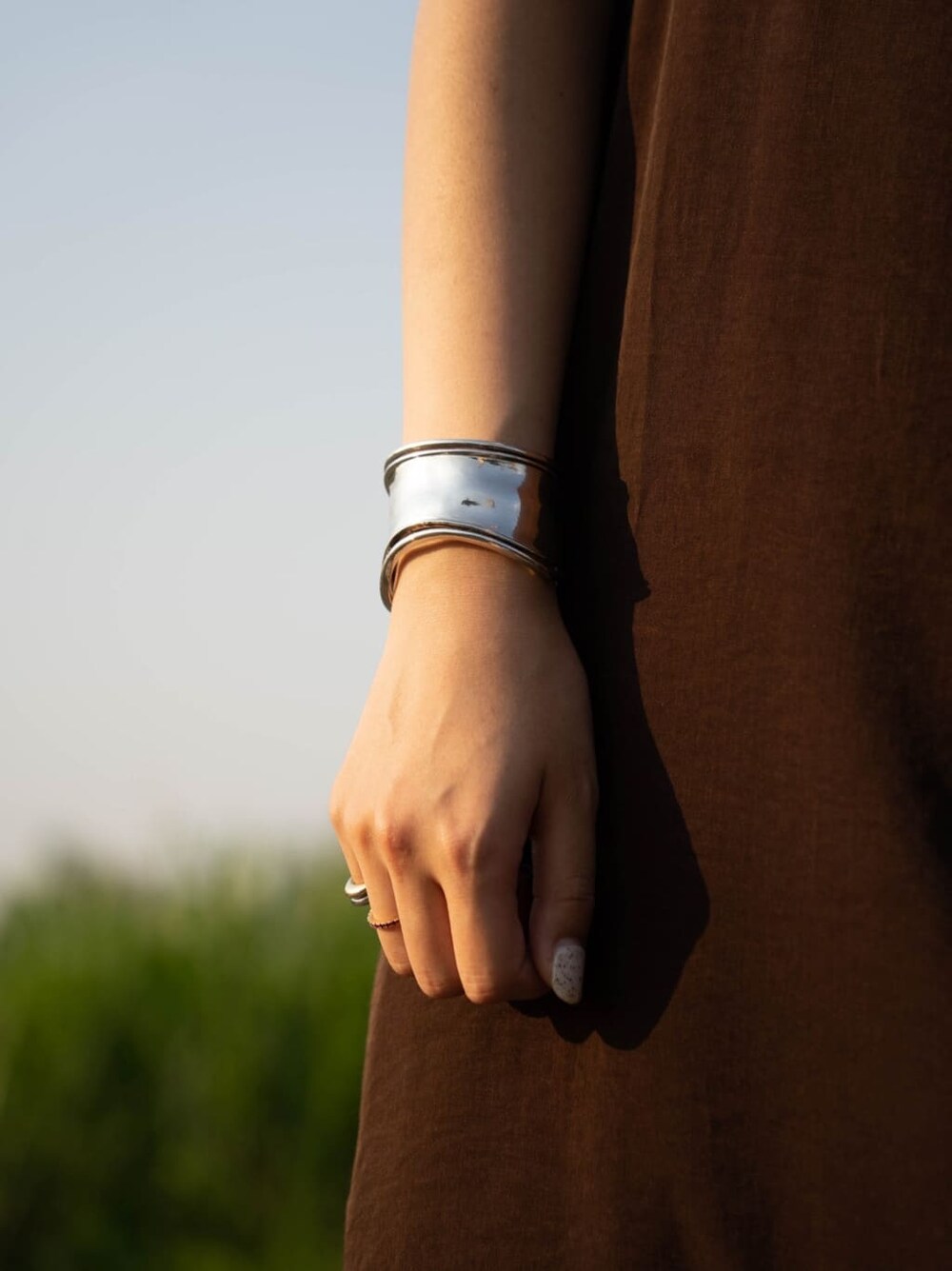 ブラウン系のワンピース、シルバー系のバングル/リストバンドを着用したレディースの夏コーディネートの7枚目の写真