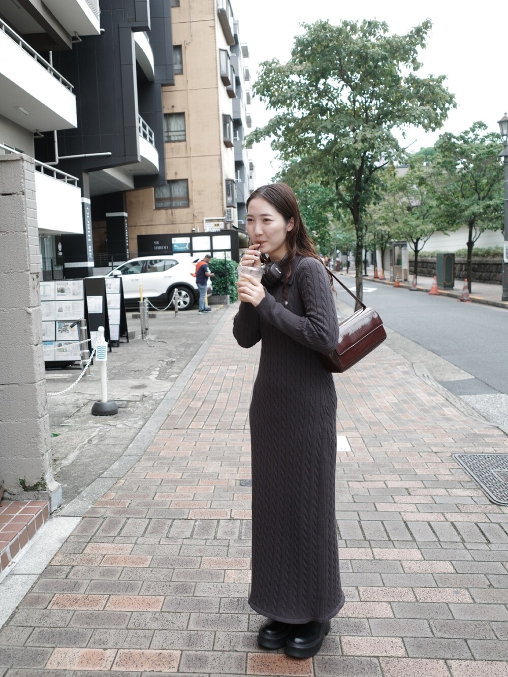 グレー系のワンピース、ホワイト系のブルゾン、ブラック系のブーツを着用したレディースの夏コーディネートの6枚目の写真