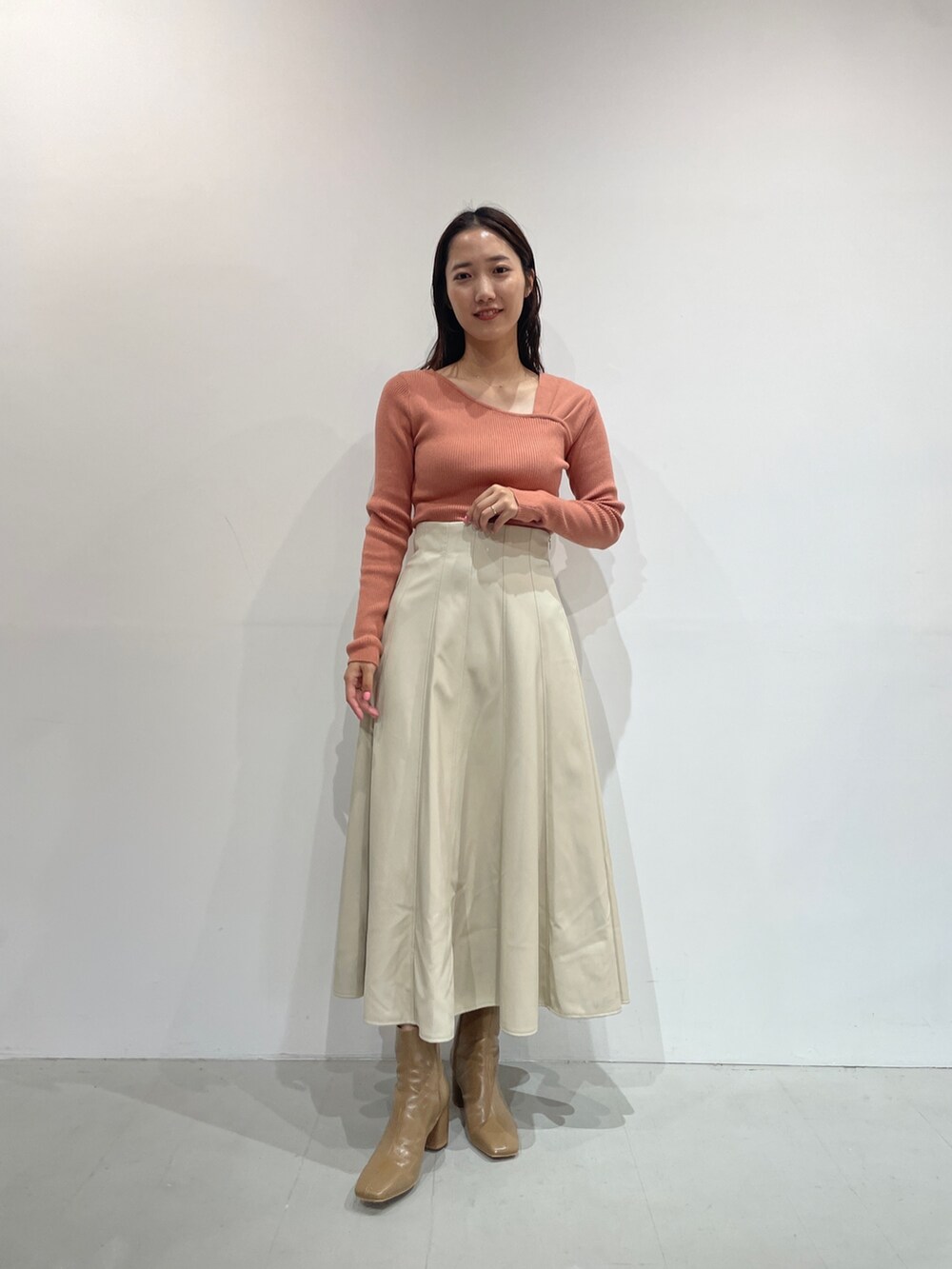 ホワイト系のスカート、ベージュ系のブーツ、オレンジ系のニット/セーターを着用したレディースの夏コーディネートの7枚目の写真