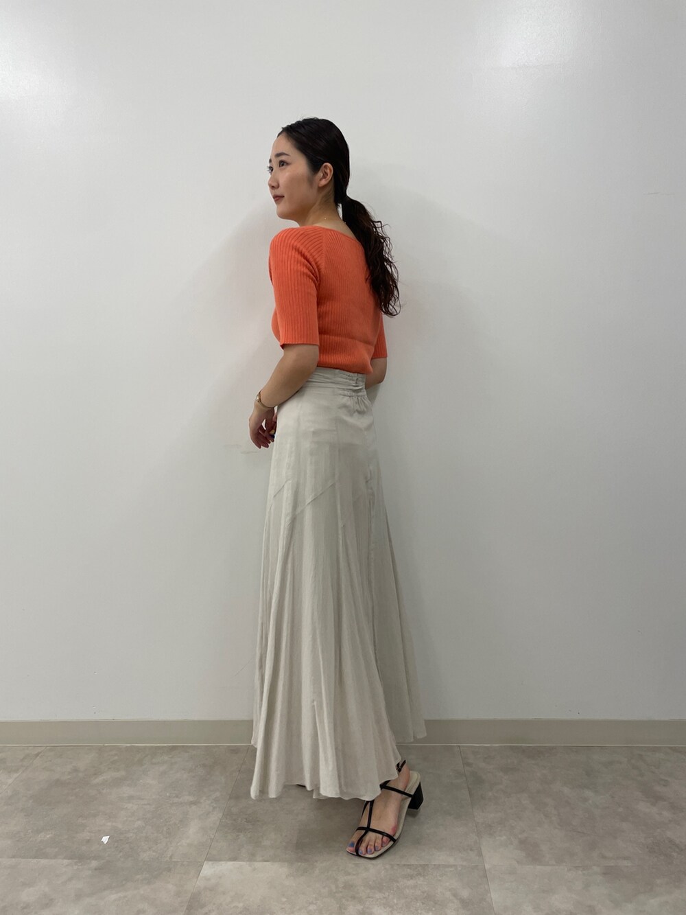 グレー系のスカート、ピンク系のニット/セーター、ブラック系のサンダルを着用したレディースの夏コーディネートの4枚目の写真