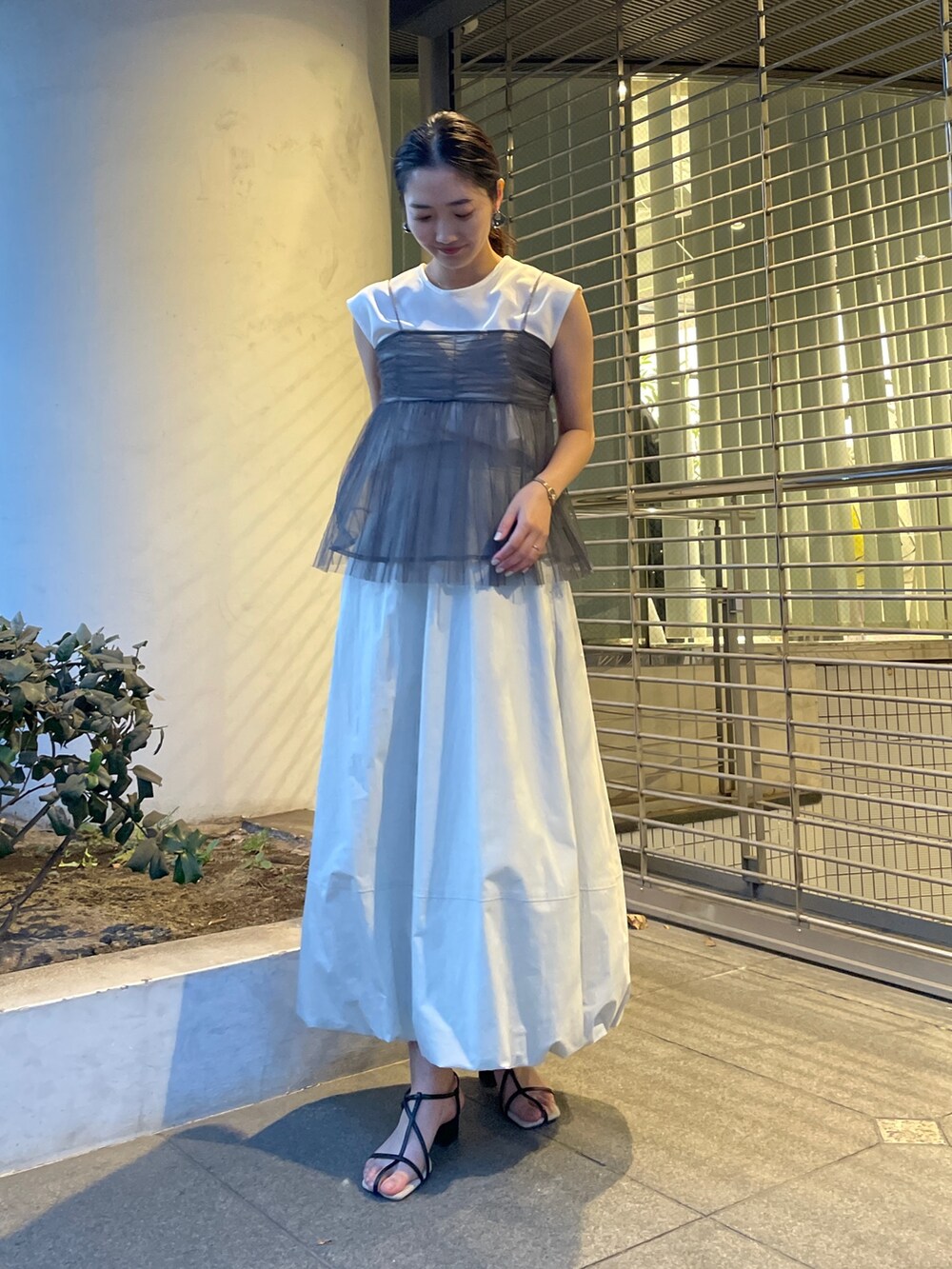 グレー系のTシャツ/カットソー、ホワイト系のスカート、ブラック系のサンダルを着用したレディースの春コーディネートの4枚目の写真