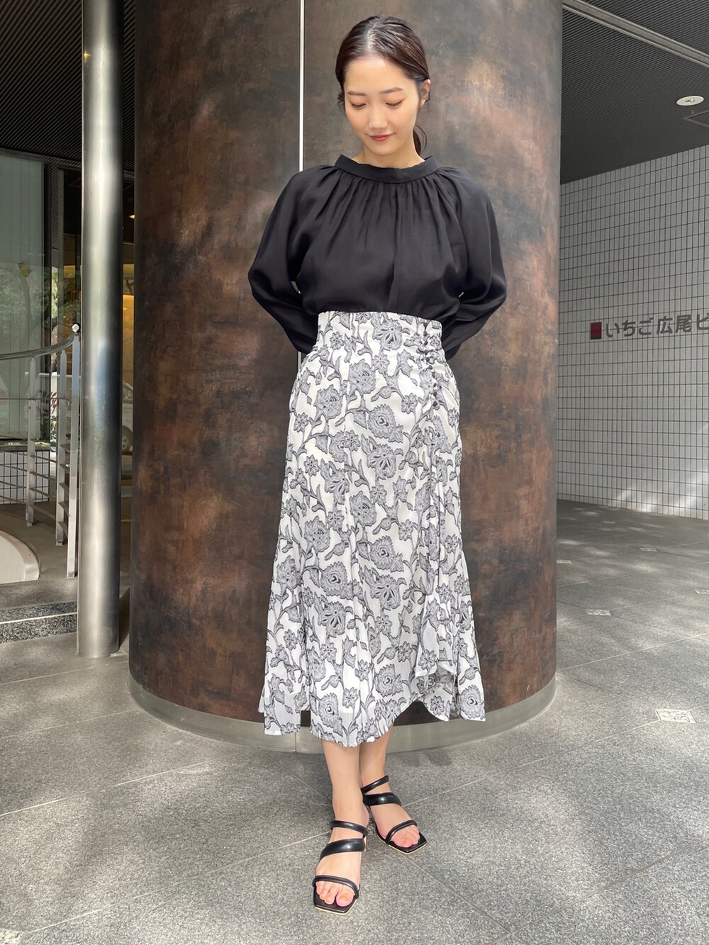 ベージュ系のサンダル、ブラック系のスカート、ブラック系のシャツ/ブラウスを着用したレディースの冬コーディネートの2枚目の写真