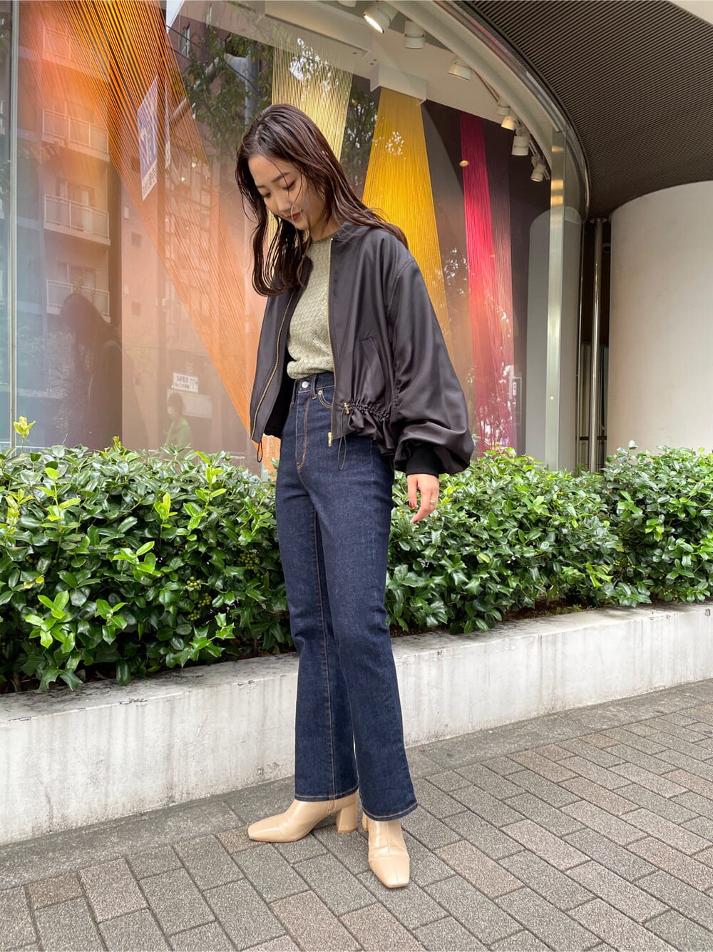 ベージュ系のシャツ/ブラウス、ブラック系のブルゾン、ブルー系のデニムパンツを着用したレディースの秋コーディネートの2枚目の写真