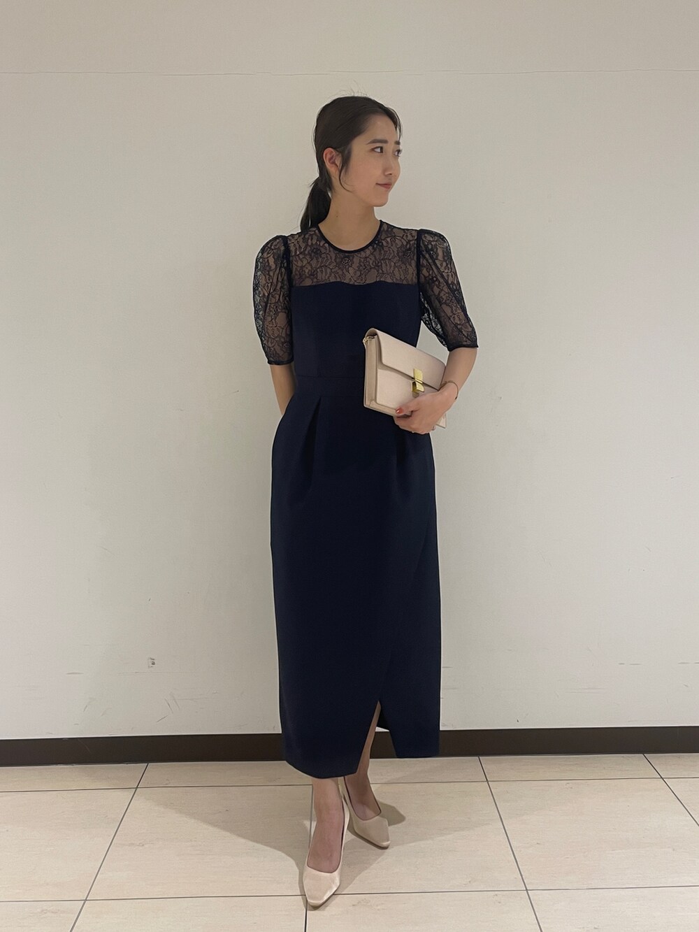 ゴールド系のクラッチバッグ、ベージュ系のパンプス、ブルー系のドレスを着用したレディースの春コーディネートの4枚目の写真