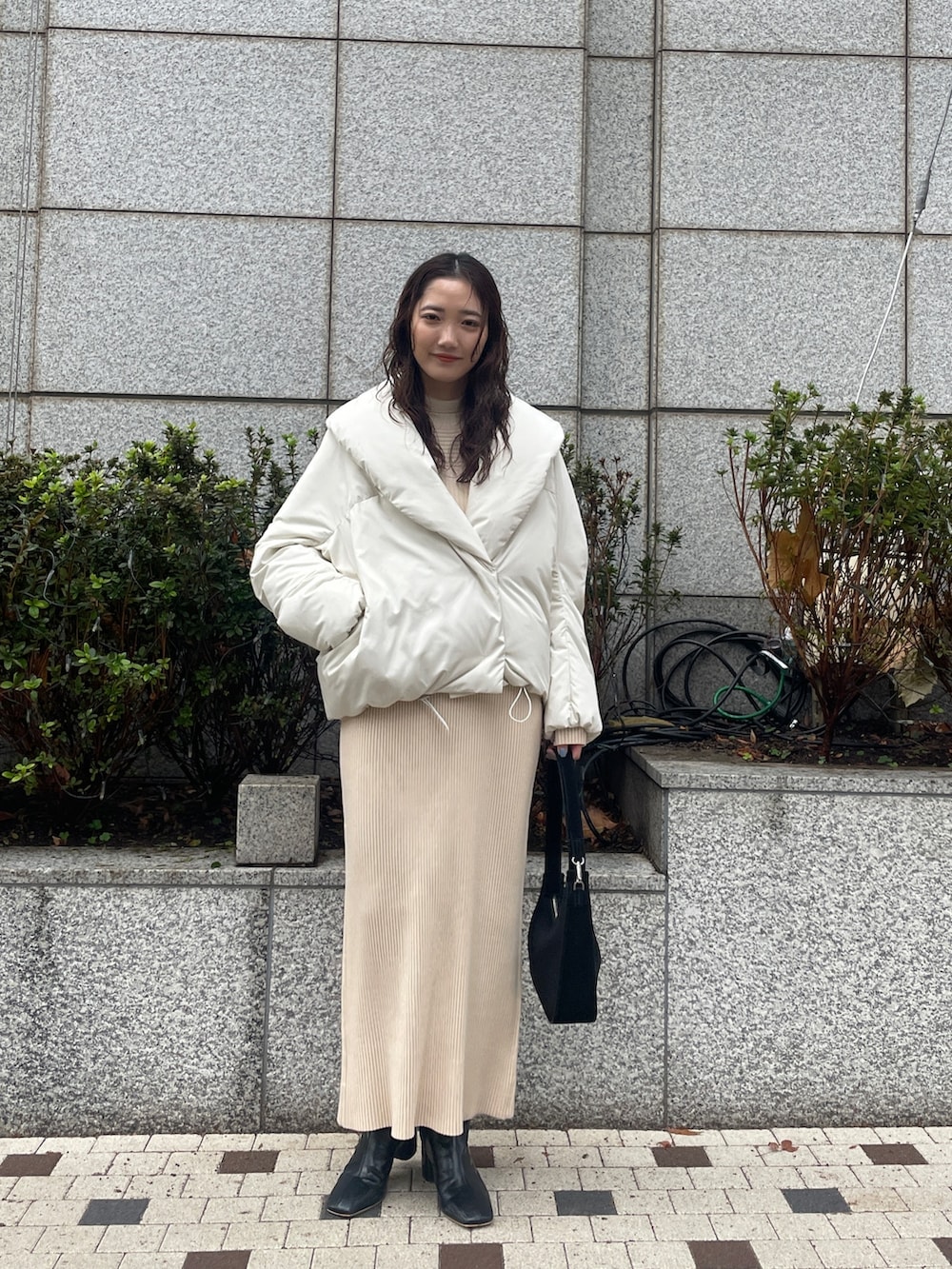 ホワイト系のダウンジャケット/コート、ベージュ系のワンピース、ブラック系のブーツを着用したレディースの冬コーディネートの2枚目の写真