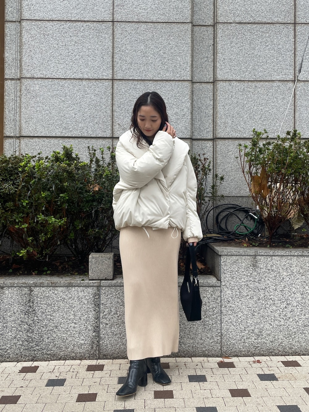 ホワイト系のダウンジャケット/コート、ベージュ系のワンピース、ブラック系のブーツを着用したレディースの冬コーディネートの3枚目の写真