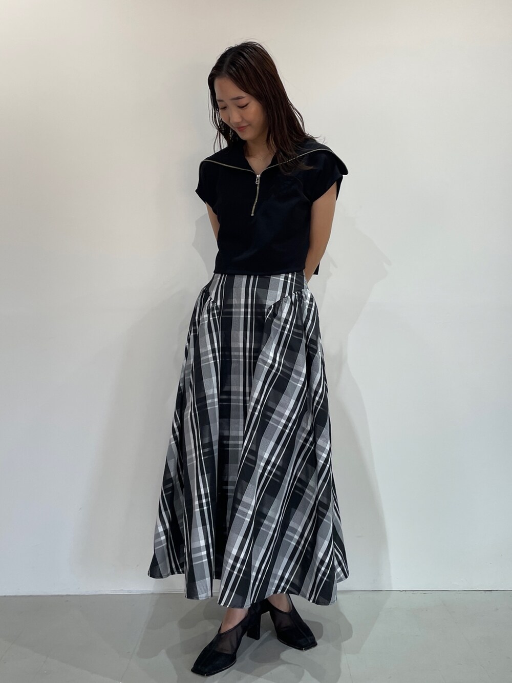 ブラック系のTシャツ/カットソー、ブラック系のパンプス、ホワイト系のスカートを着用したレディースの夏コーディネートの3枚目の写真