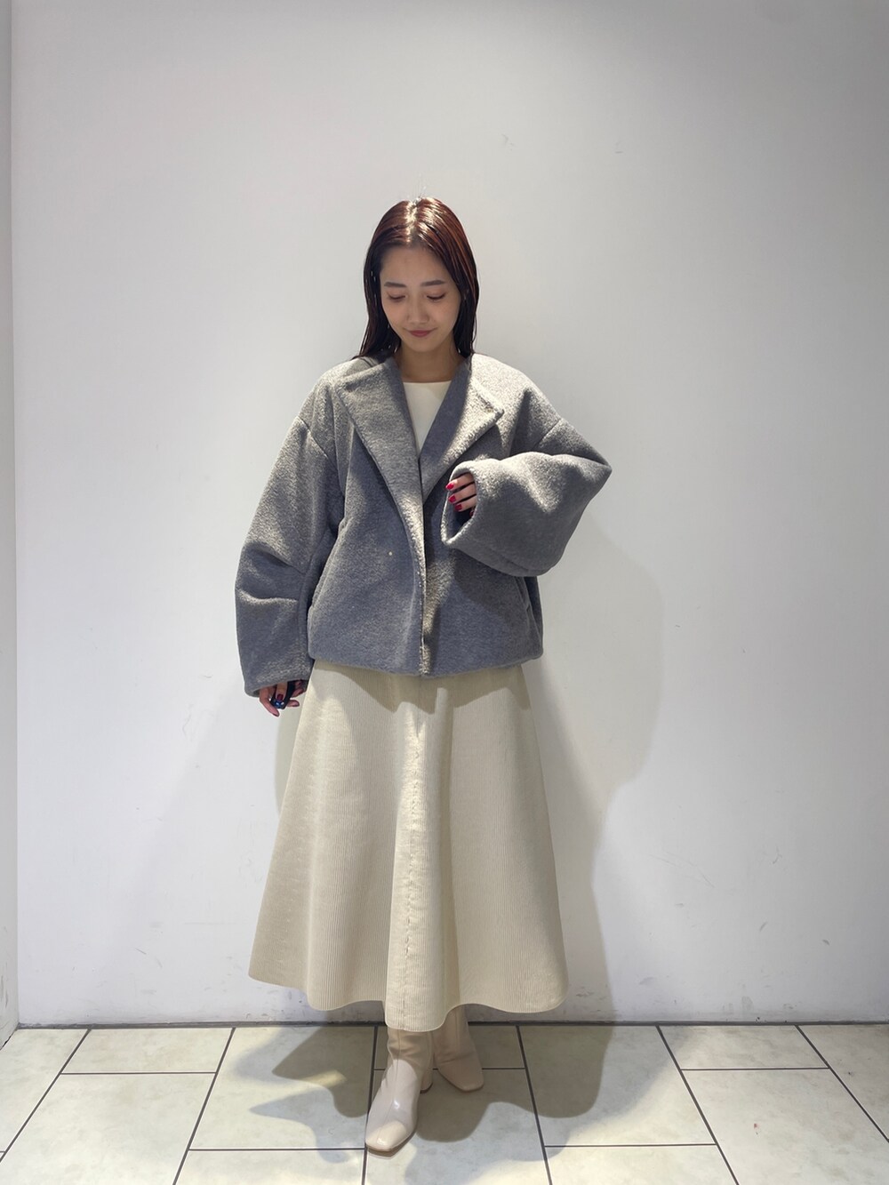 グレー系のブルゾン、ホワイト系のブーツ、ホワイト系のジャンパースカートを着用したレディースの秋コーディネートの3枚目の写真