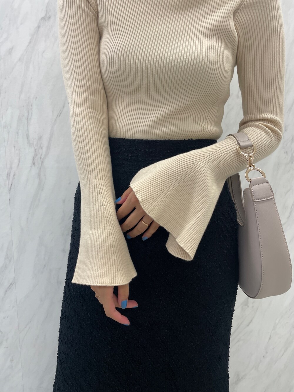 ブラック系のブーツ、ホワイト系のハンドバッグ、ブラック系のスカートを着用したレディースの秋コーディネートの9枚目の写真