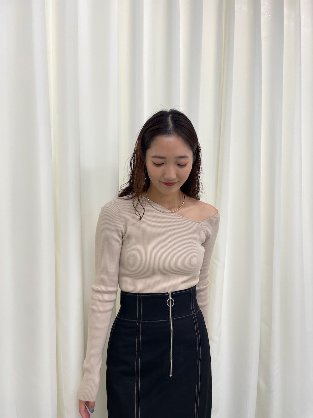 ブラック系のスカート、ベージュ系のニット/セーター、ホワイト系のパンプスを着用したレディースの冬コーディネートの3枚目の写真