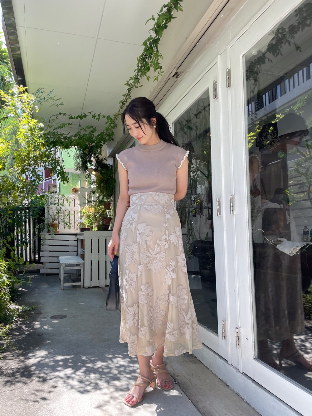 ベージュ系のサンダル、ベージュ系のニット/セーター、ベージュ系のスカートを着用したレディースの春コーディネートの2枚目の写真