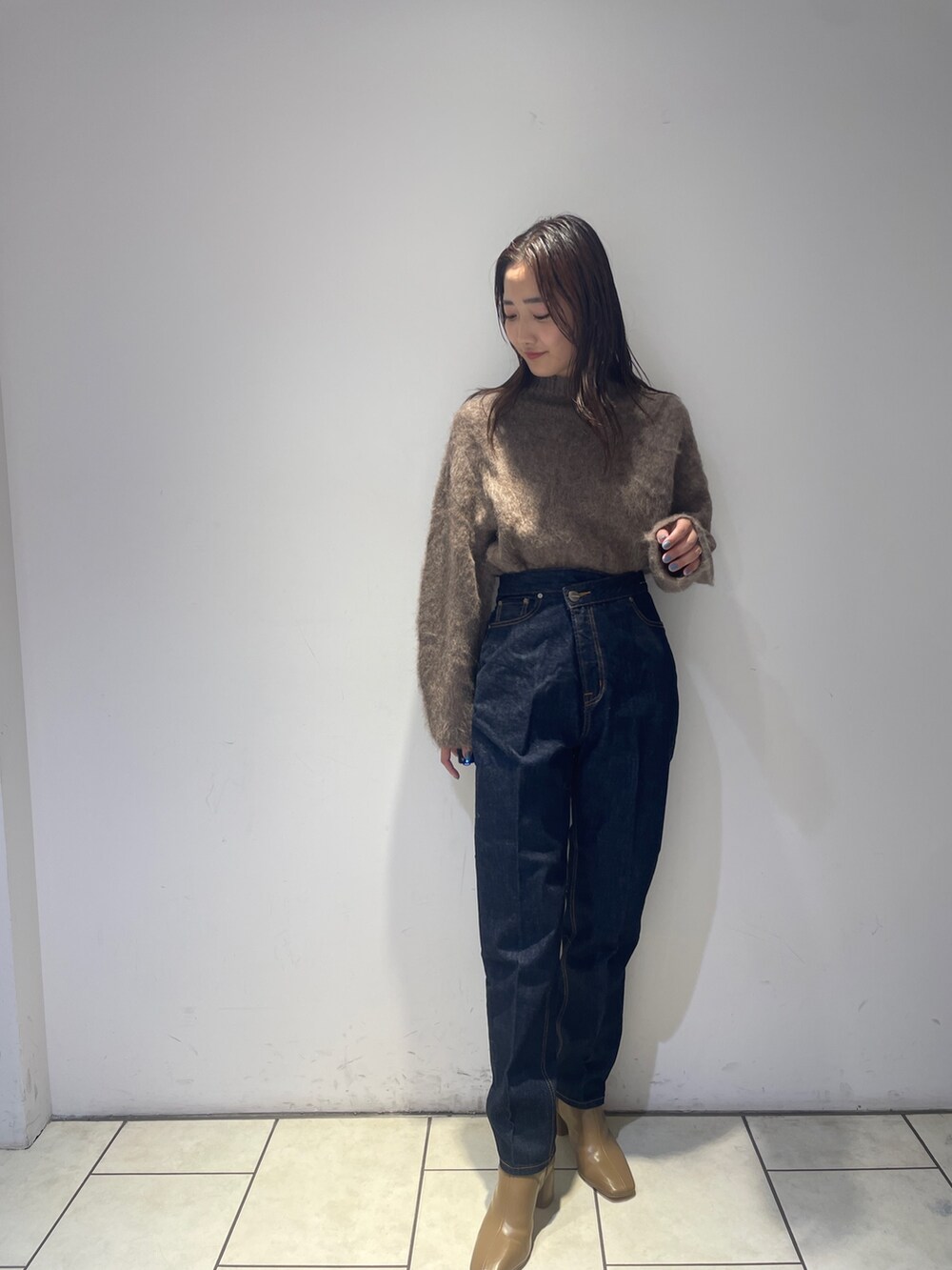 ブラウン系のニット/セーター、ベージュ系のブーツ、ブルー系のデニムパンツを着用したレディースの秋コーディネートの2枚目の写真