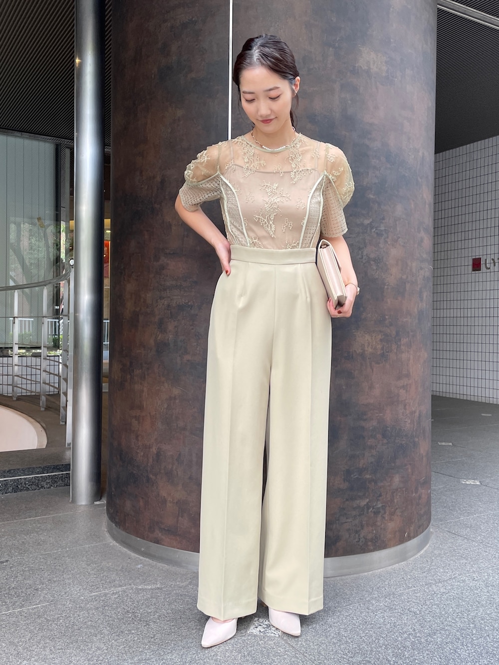 グリーン系のパンツドレス、ベージュ系のクラッチバッグ、ベージュ系のパンプスを着用したレディースの冬コーディネートの4枚目の写真