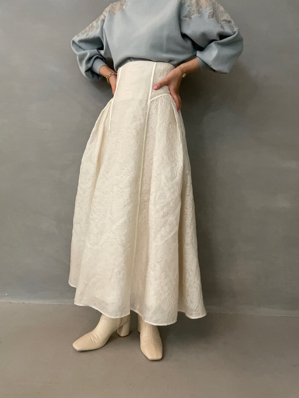 グレー系のニット/セーター、ホワイト系のスカート、ホワイト系のブーツを着用したレディースの夏コーディネートの7枚目の写真