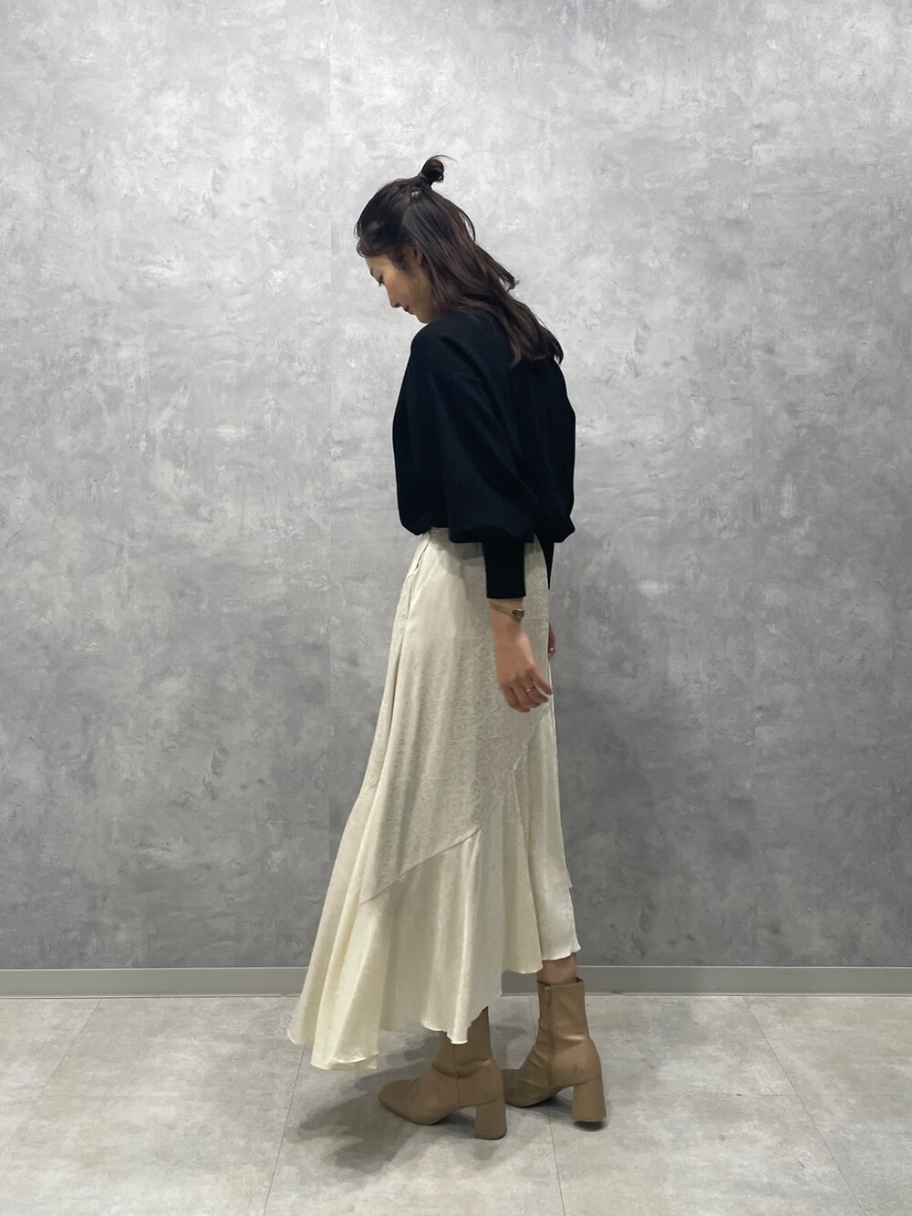 ブラック系のニット/セーター、ホワイト系のスカート、ベージュ系のブーツを着用したレディースの冬コーディネートの5枚目の写真